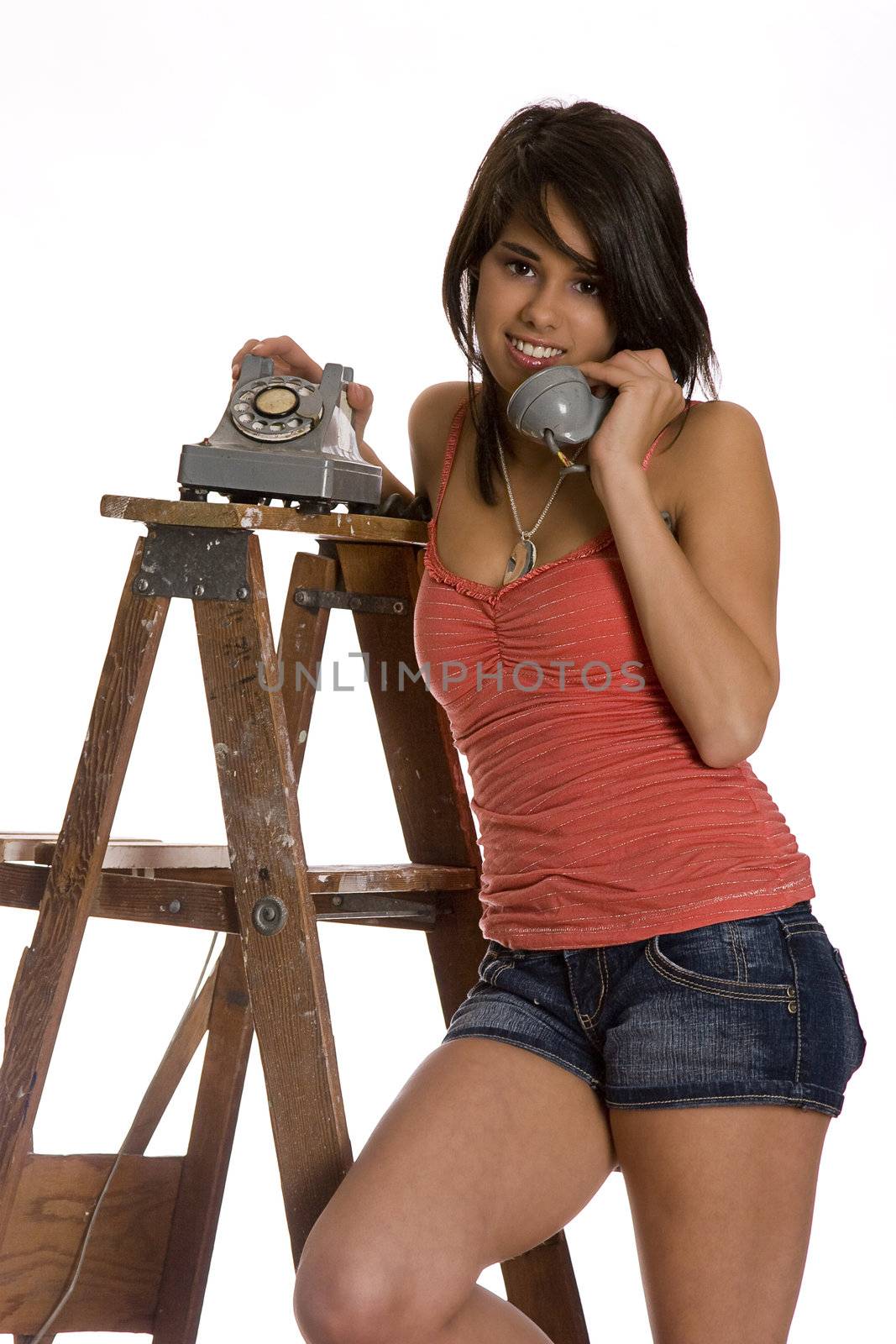 teenage girl standing on ladder talking on a old rotary phone, looking at the camera