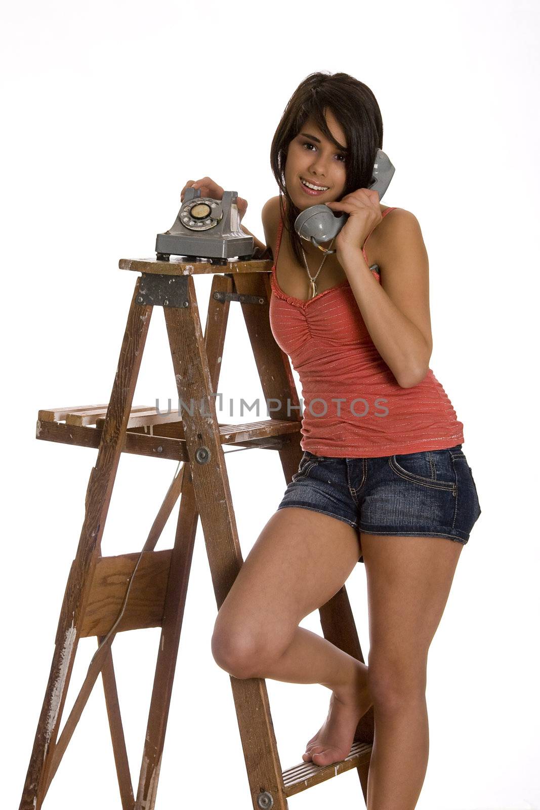 teenage girl standing barefoot on ladder talking on a old rotary phone with a great big smile