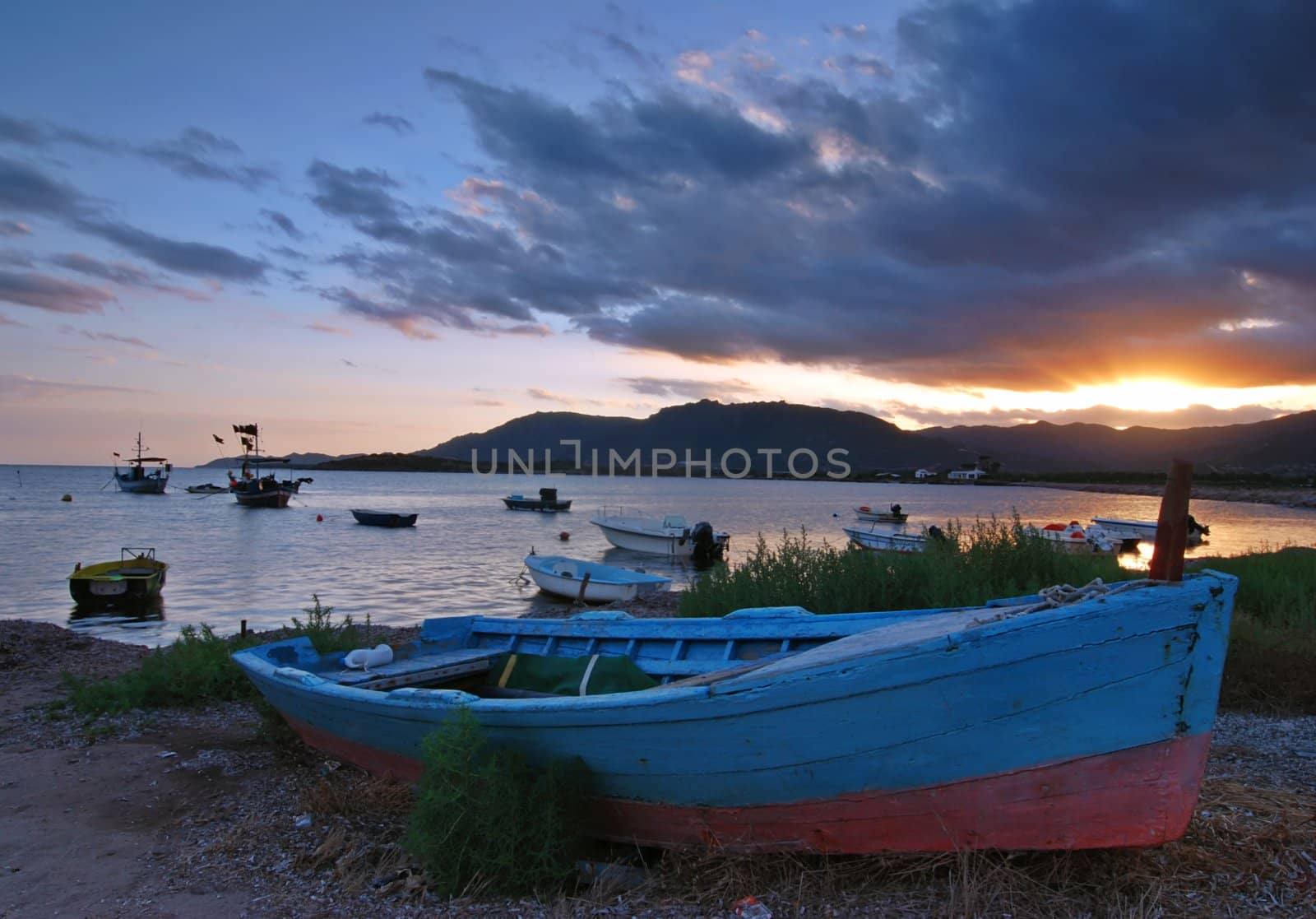 Beautiful sunset over harbor with a ship detail with dramatic sky on Sardinia