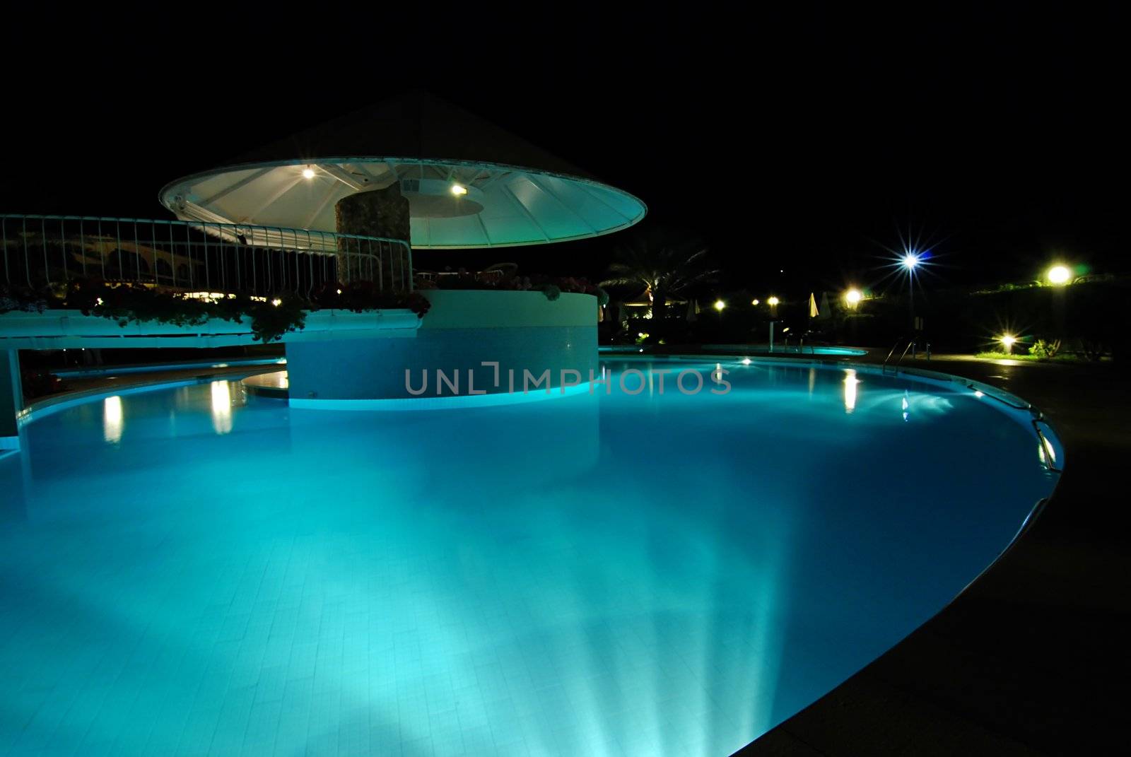 Swimming pool at night illuminated by lamps