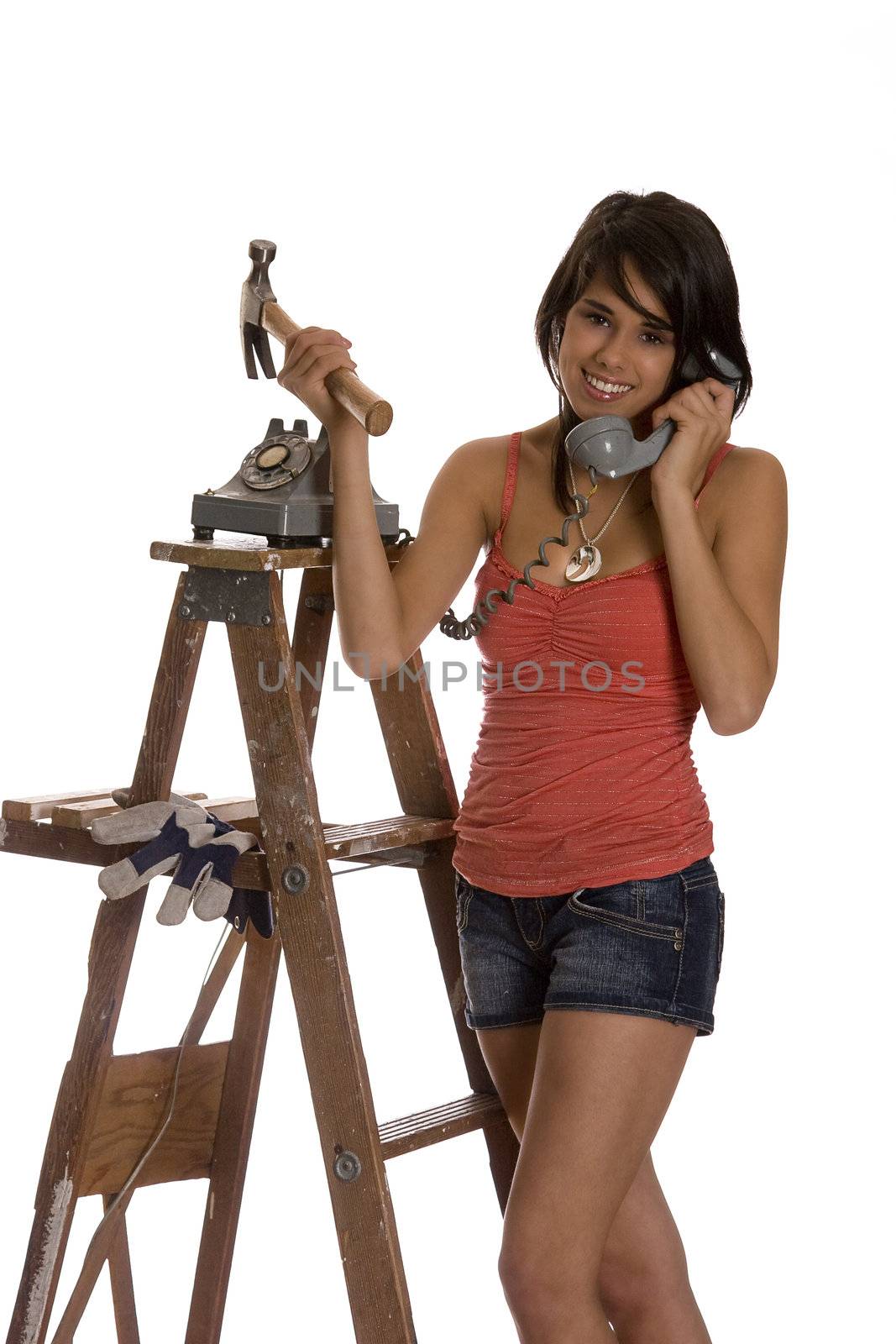 teenage girl standing on ladder talking old rotary phone with a hammer in her hand