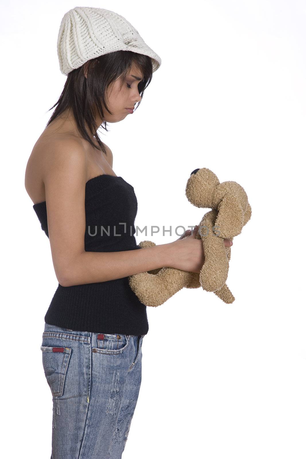 Teenage girl wearing a black tube top, knitted hat and jeans with holes holding a brown stuff dog plush toy with sad expression
