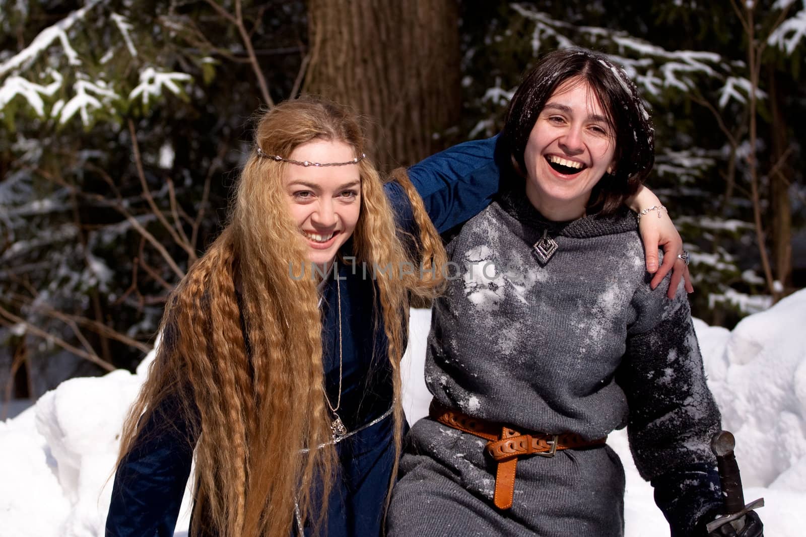 Two ladies in medieval dresses in winter forest
