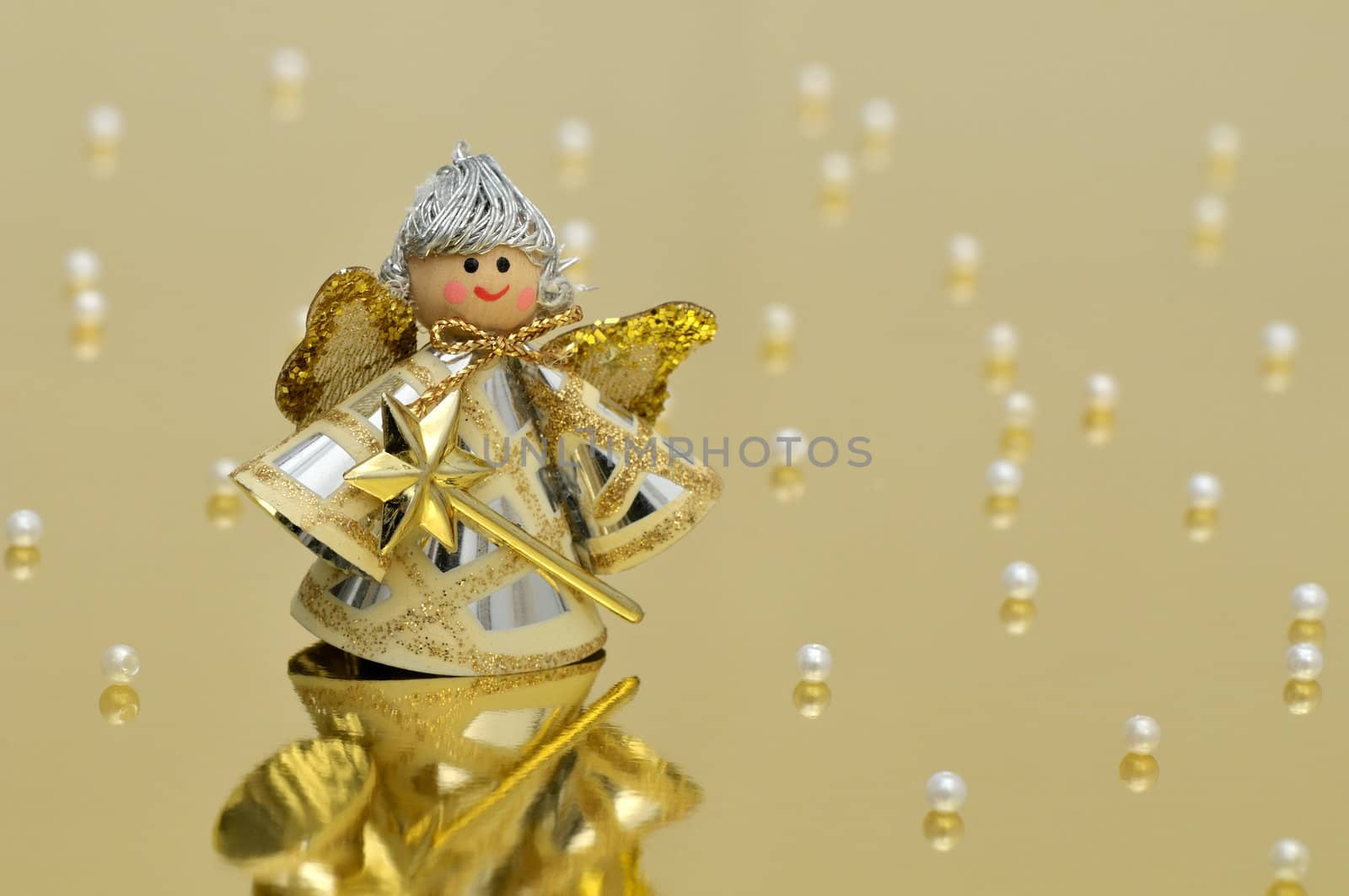 Vintage handmade angel decoration on glossy golden background with pearls