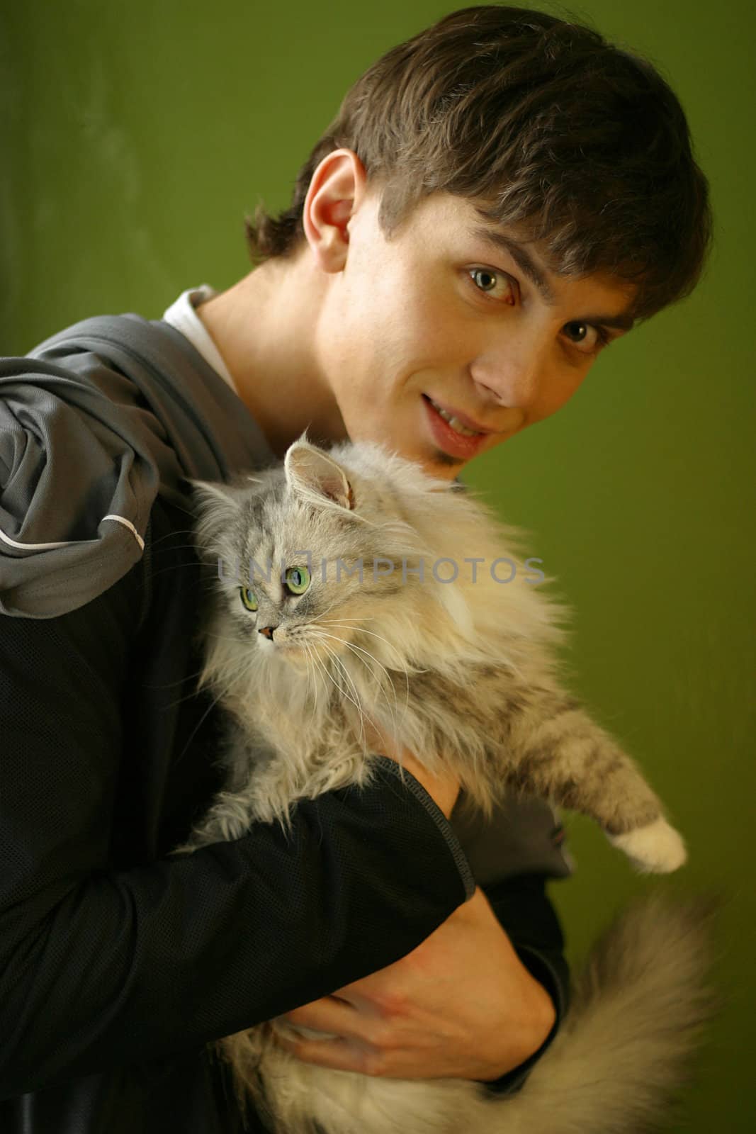 The young man covers a kitten on a green background