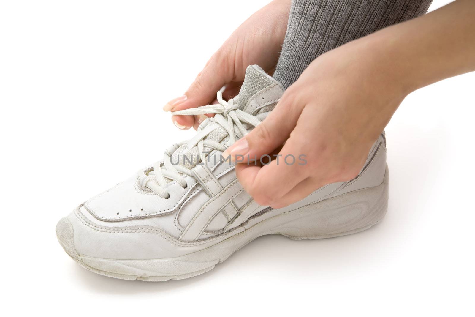 Woman tying her running shoes. White background.