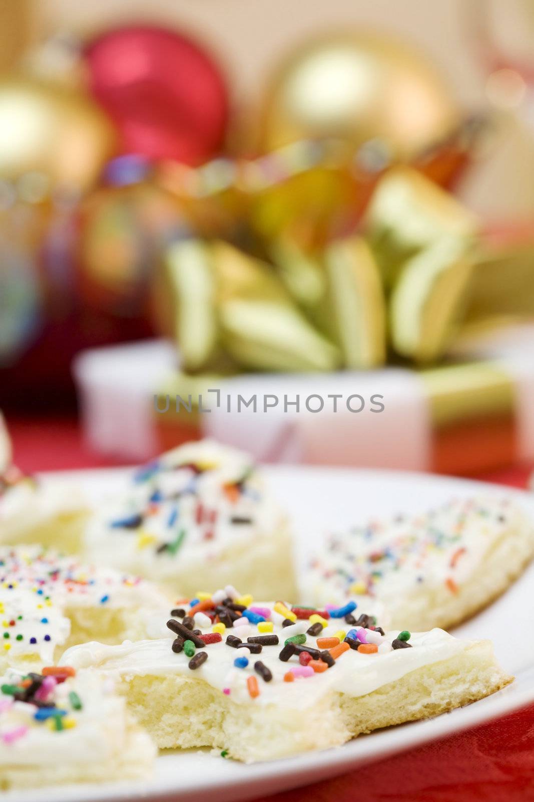 Frosted cake pieces with sprinkles, present and Christmas decorations in background