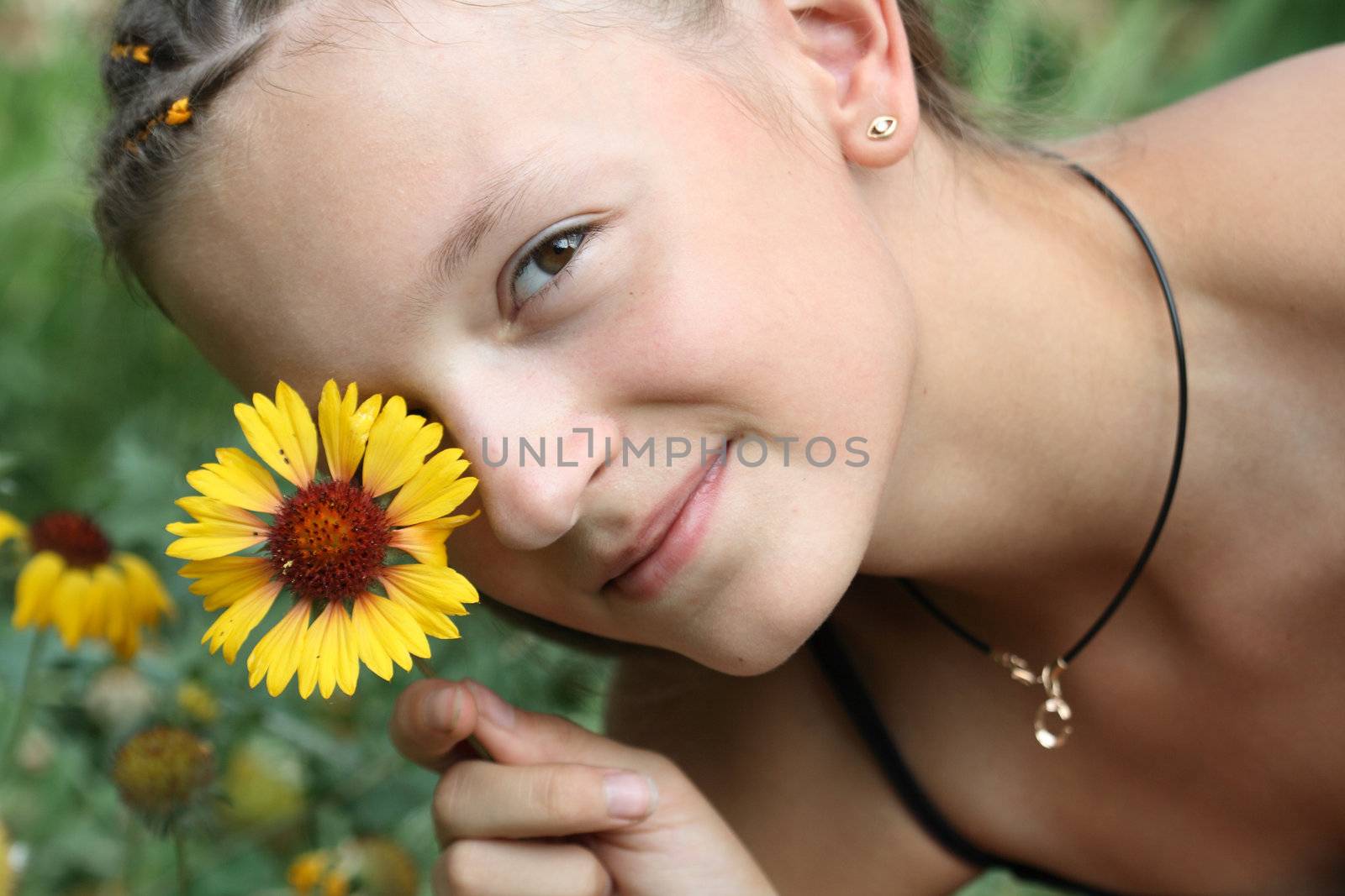 Portrait of nice young girl handing yellow flower near her face
