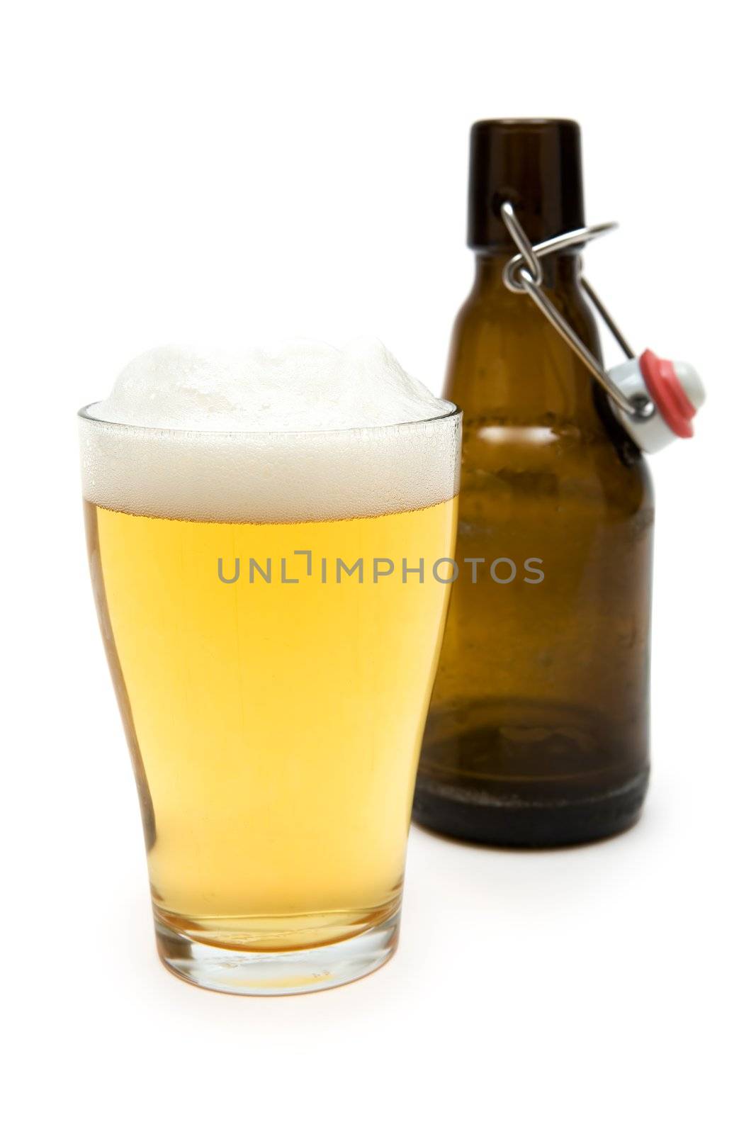 Glass of beer and empty bottle. White background. Shallow depth of field.
