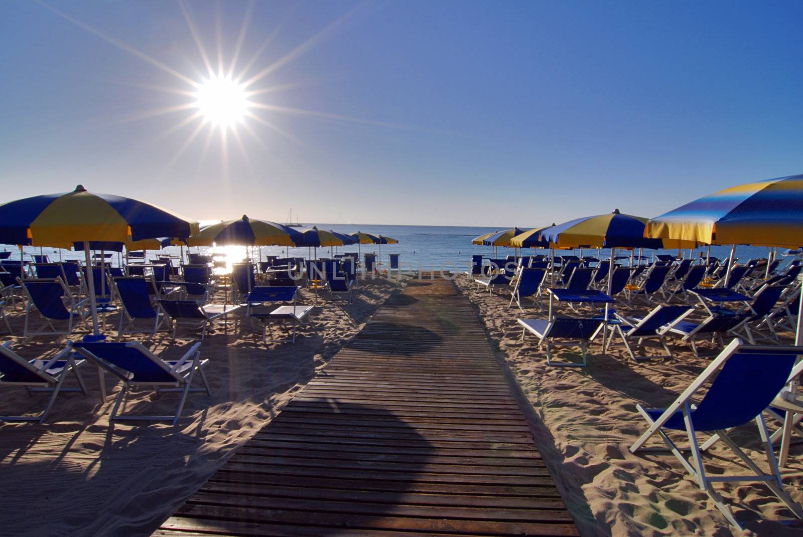 Empty beach with umbrellas and sun shortly after the sunrise