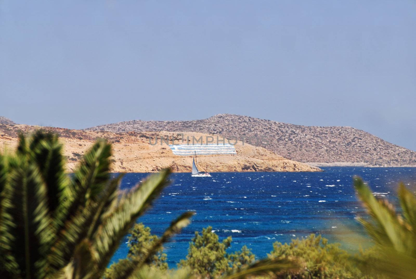 Greek paradise - boat under the flag of Greece, blue sea and palms