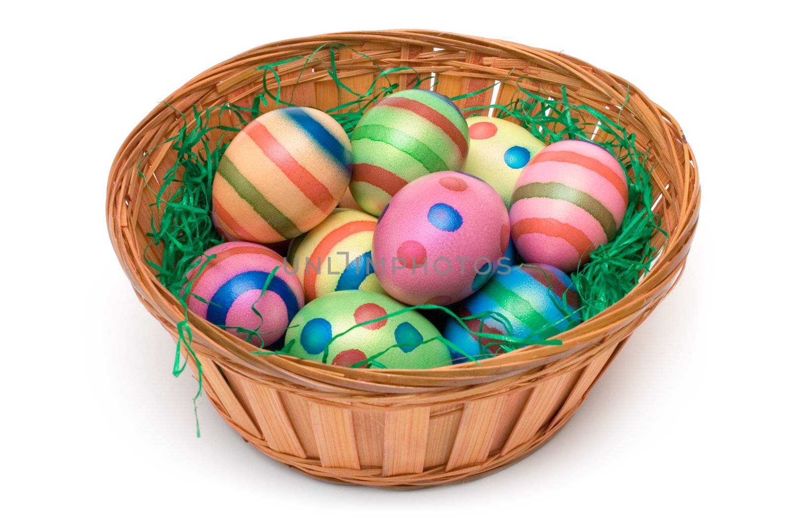 Colorful eggs on green grass in a wooden basket. Isolated on a
white background.