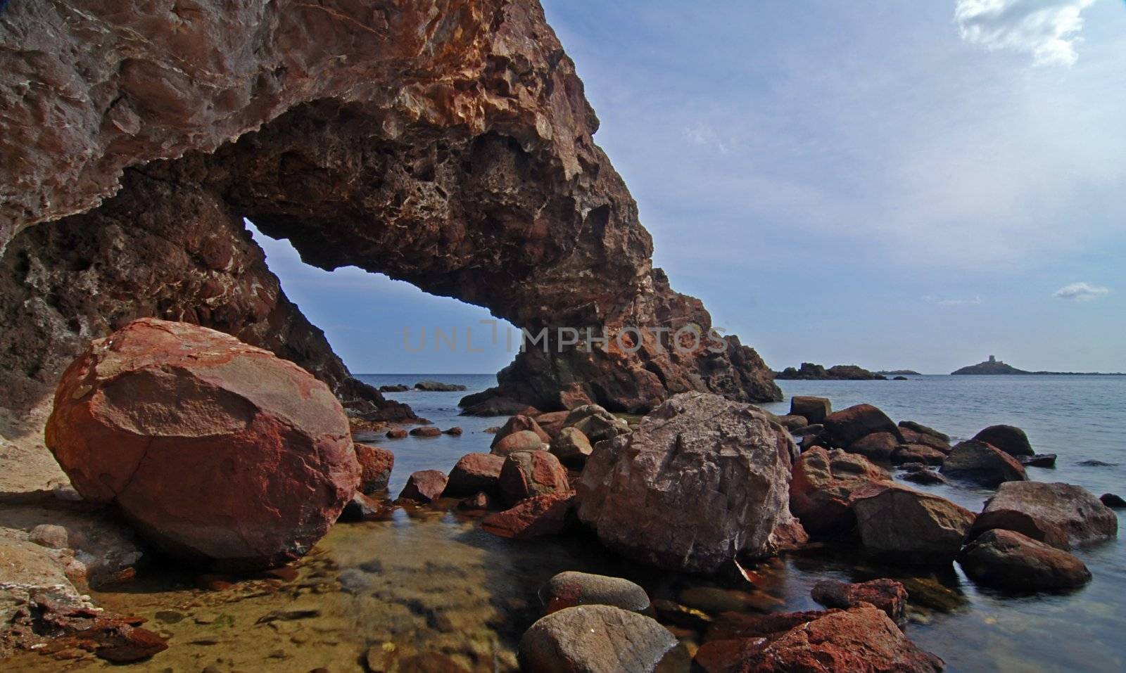 Cave in the cliff is being washed by a sea surf on Sardinia