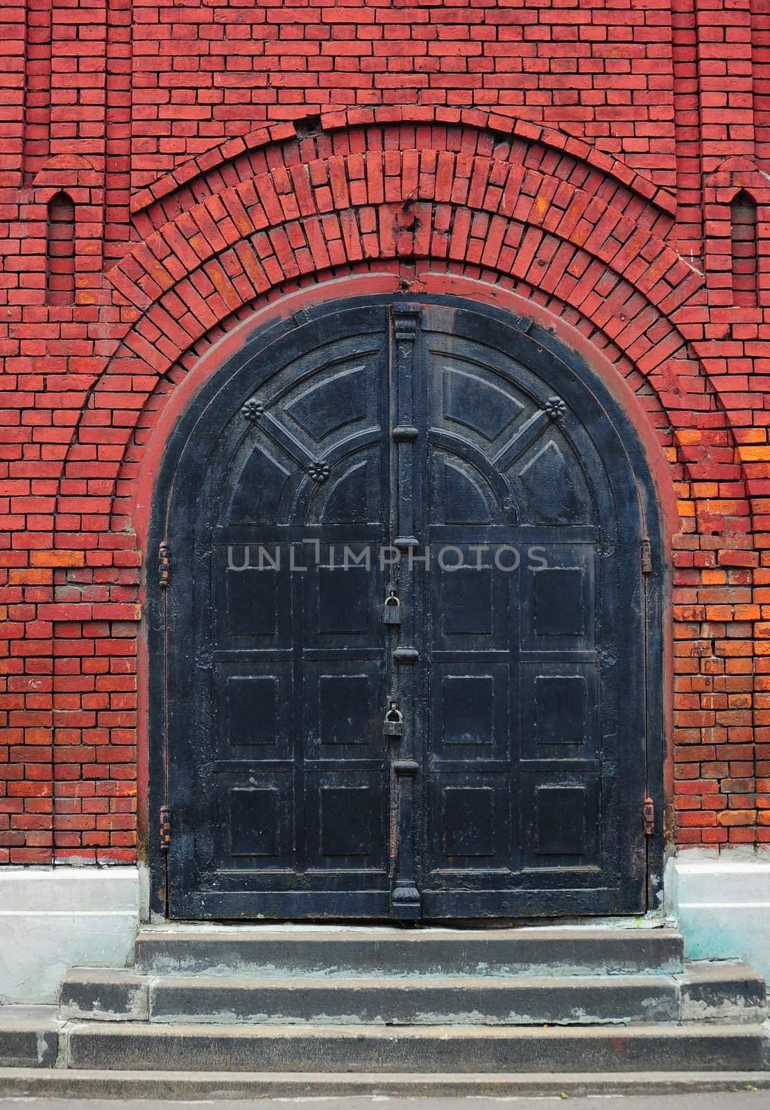 Black Metal Gate In Dark Red Brick Wall