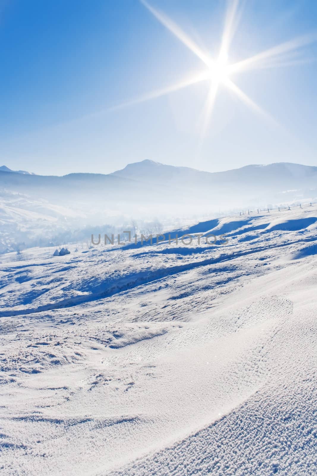 Snowcovered mountains under blue sky and shiny sun