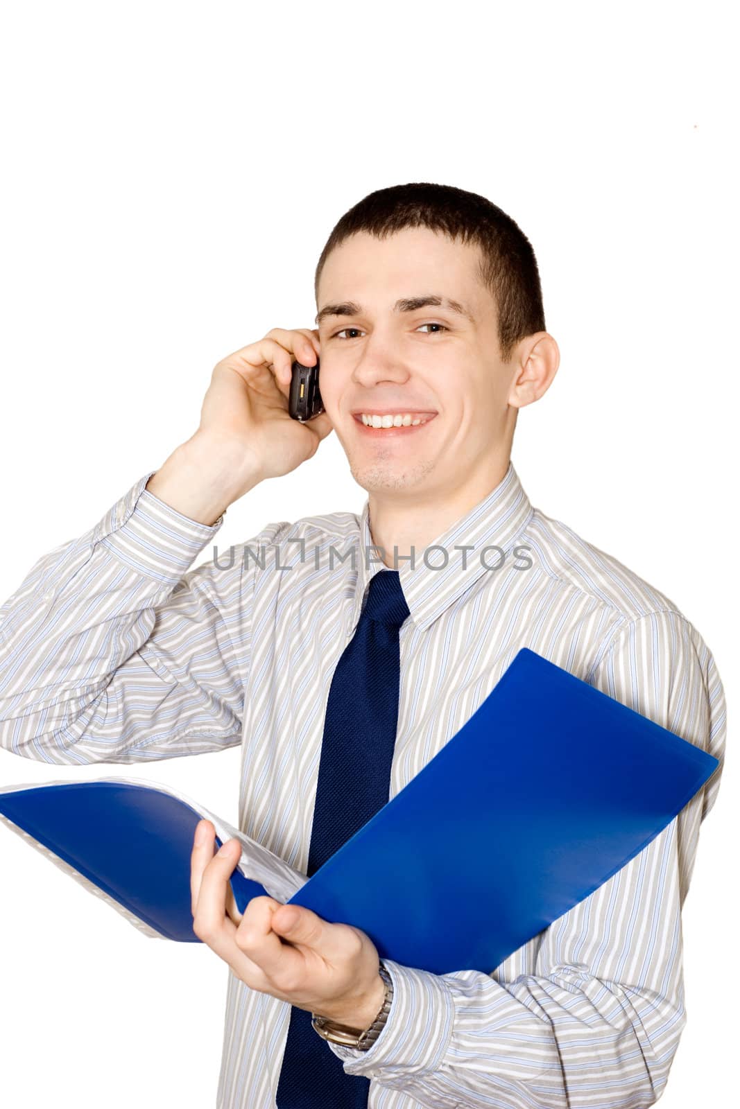 The young man holds in a hand a blue folder with documents and speaks by mobile phone