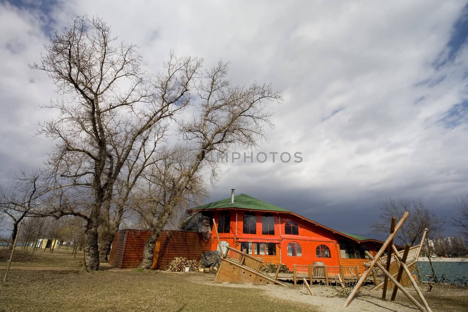 House near lake with tree and stormy clouds