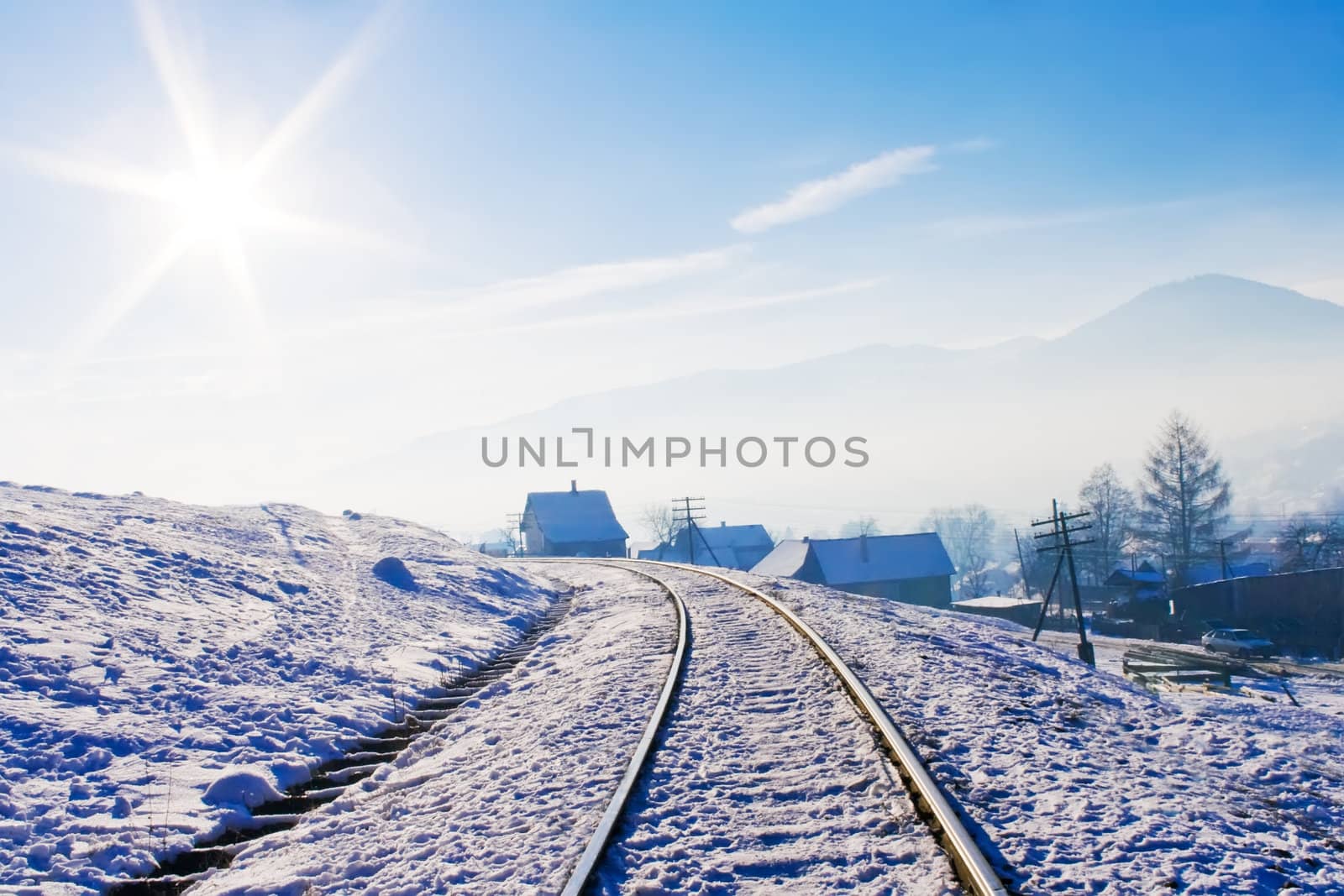 Railroad in snow covered mountains under blue sunny sky in wintertime