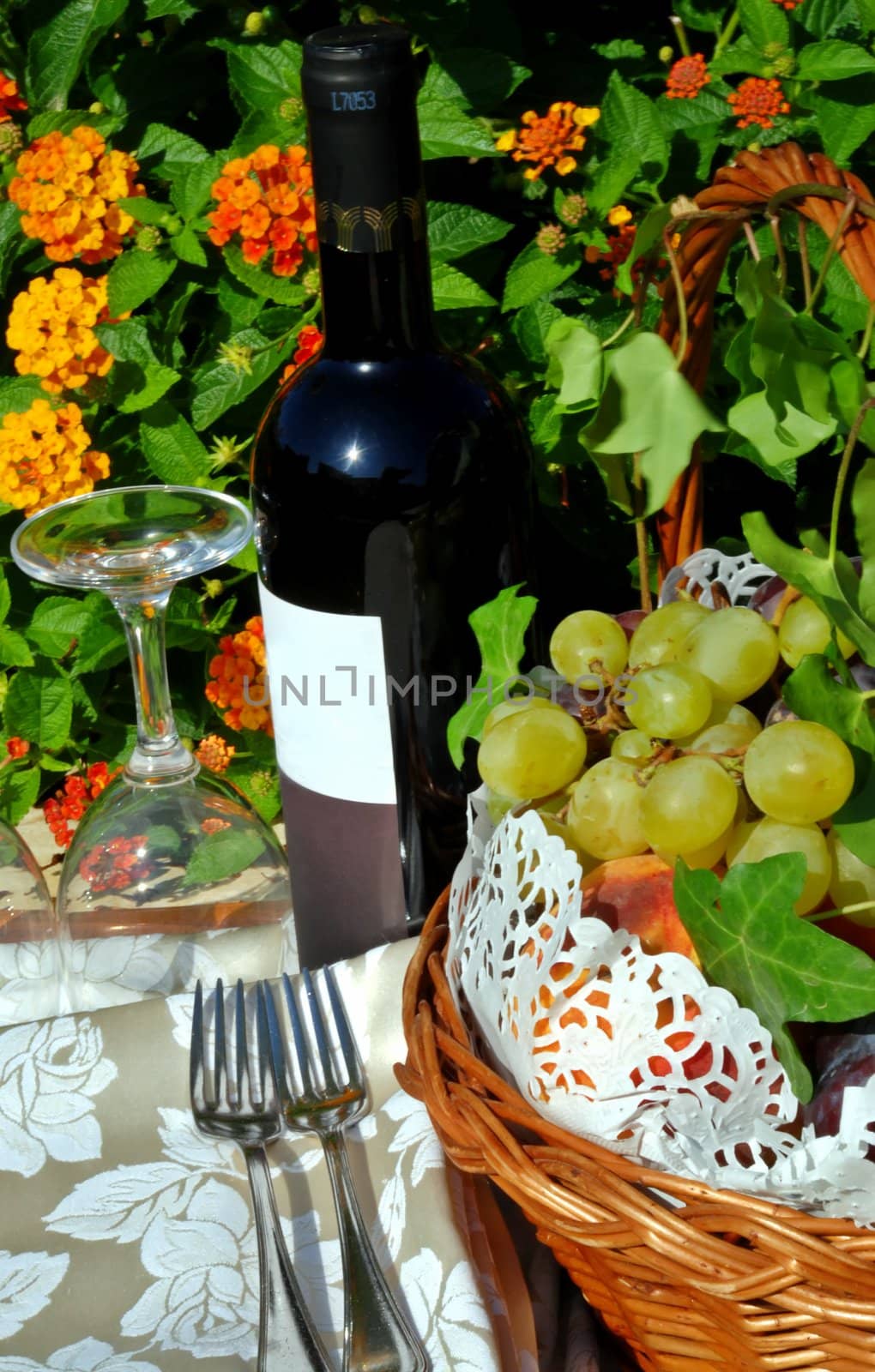 Wine still life on flower background with basket of fruits and glasses