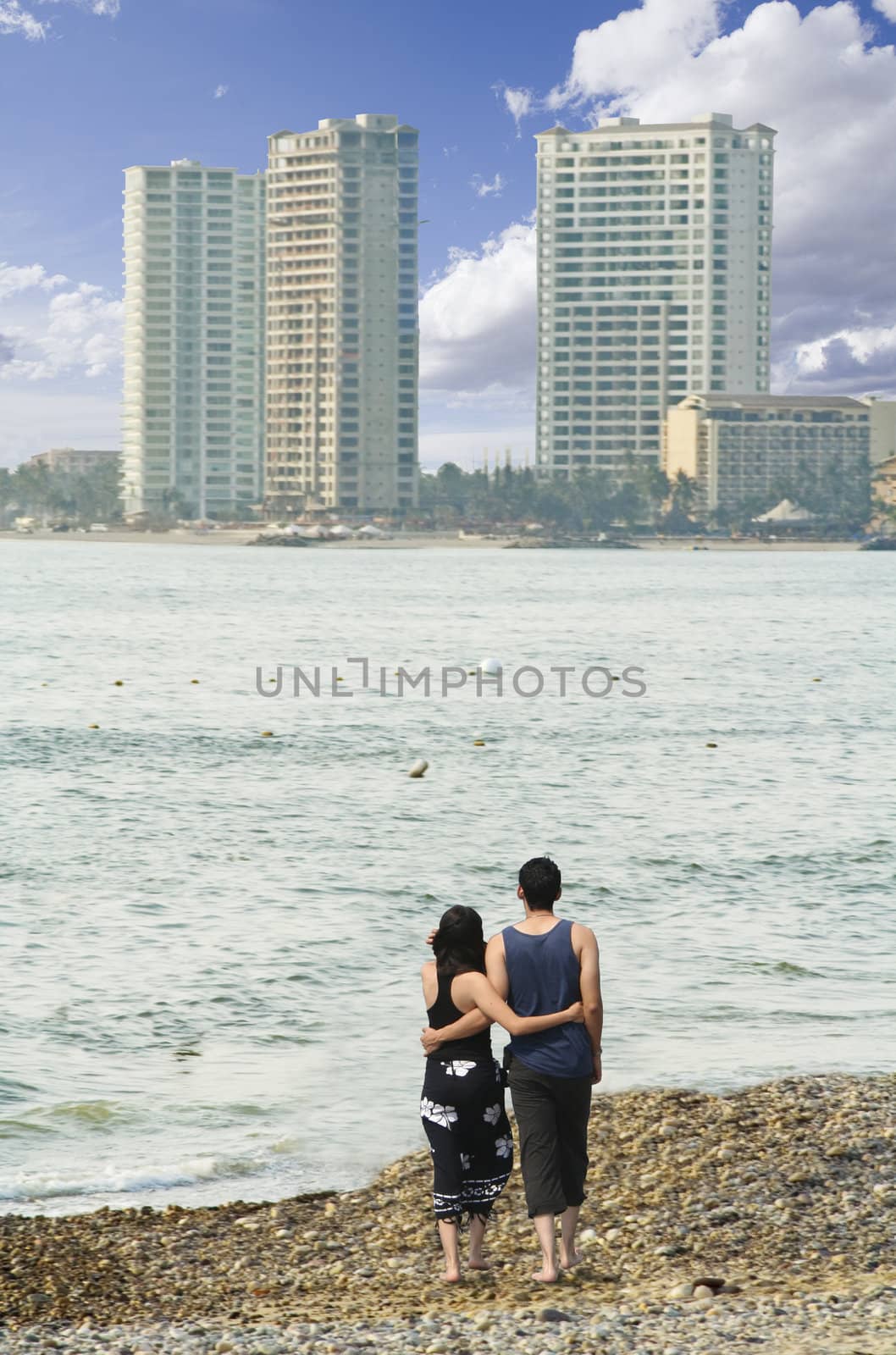 Couple walking on beach with high rise hotels