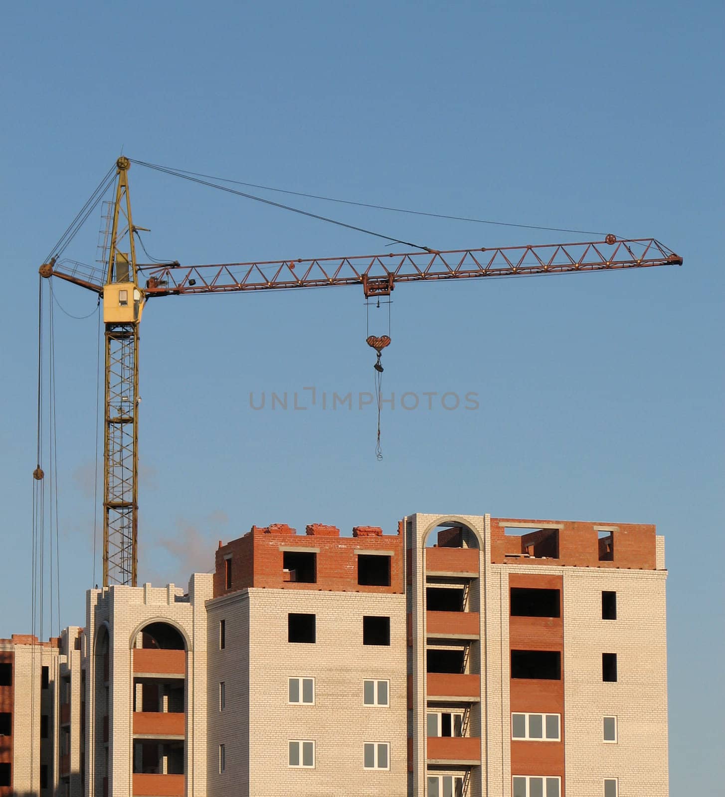 the hoisting crane on the blue sky background