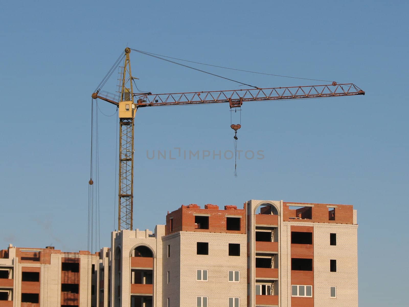 the hoisting crane on the blue sky background