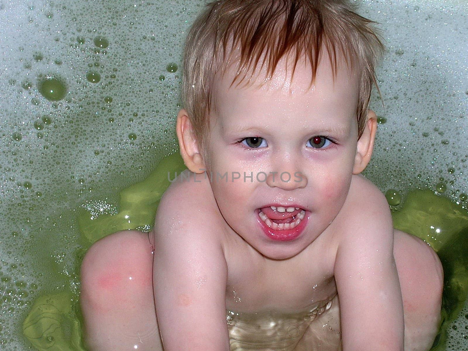 The boy bathes in a foamy bath          