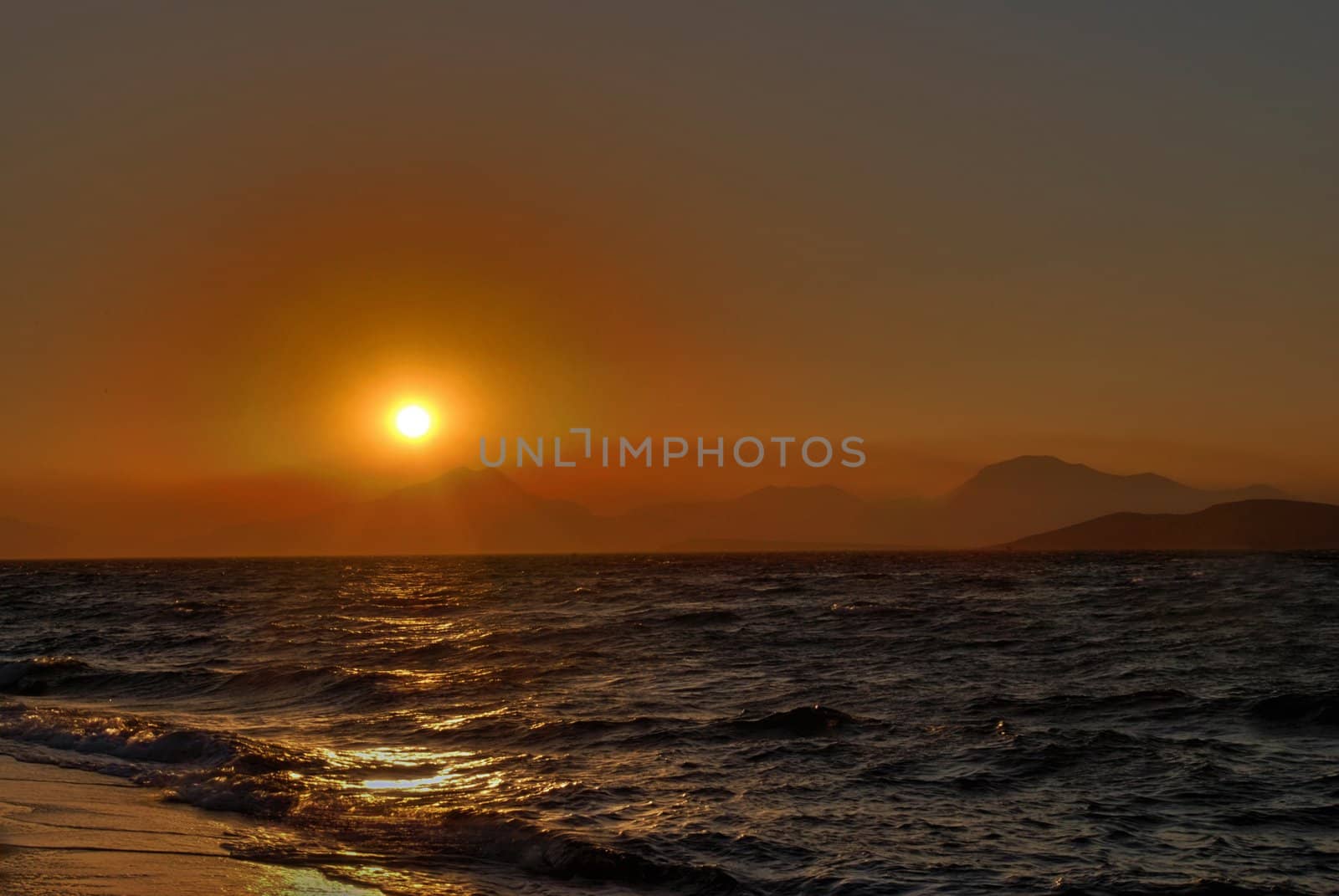 Sun is setting behind the mountains and sea