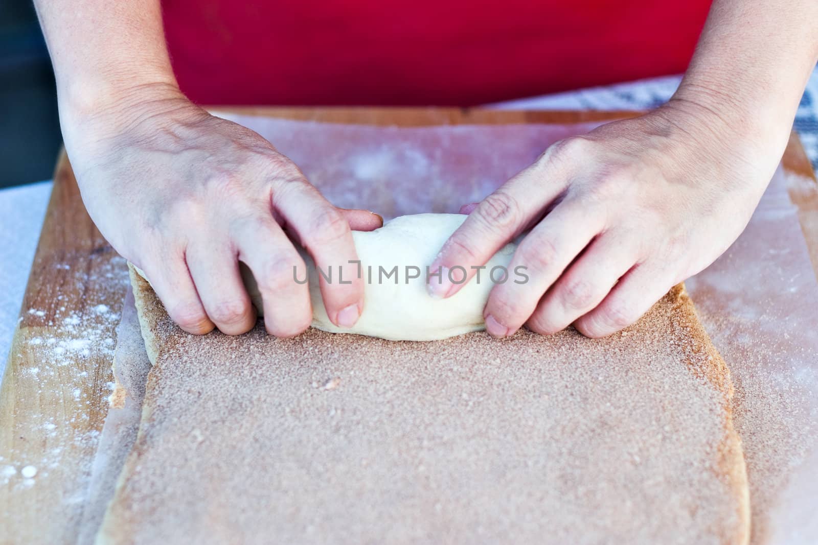 Woman hands rolling dough for cinnamon rolls. 
