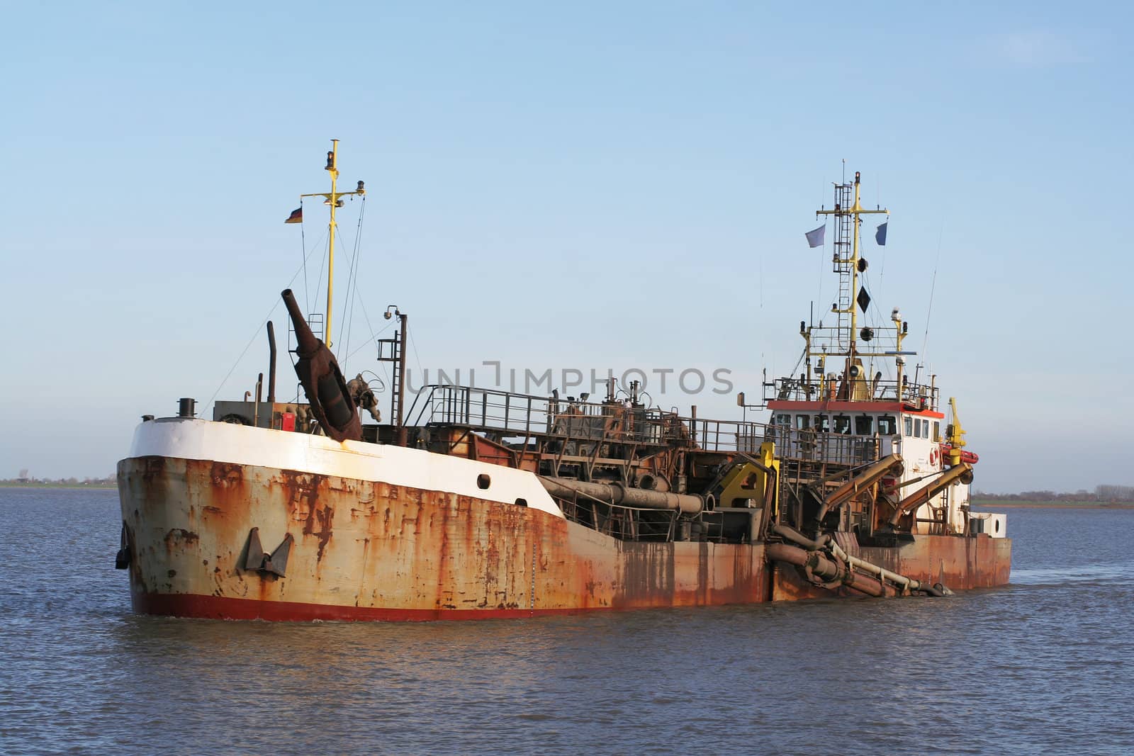 A rusty dredger ship (a trailing suction hopper dredger) on river Elbe near Wischhafen.