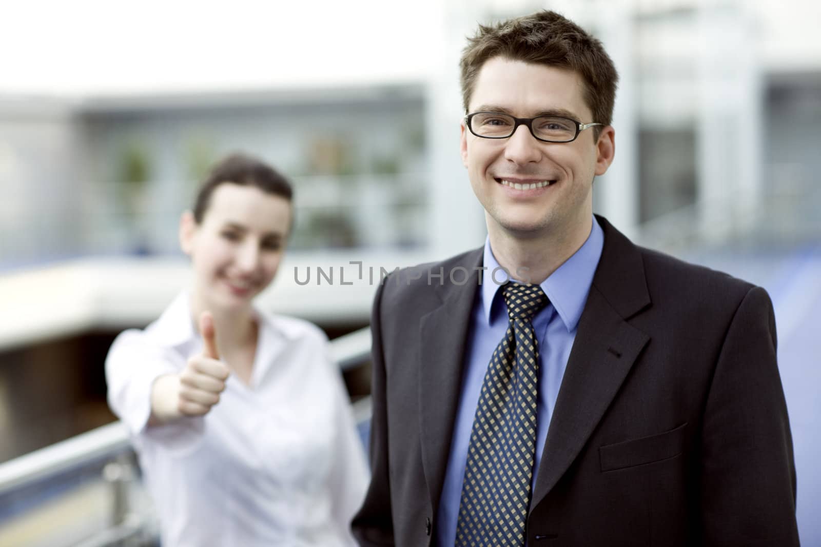 Business portrait - young handsom man with thumbs up sign in backgroud