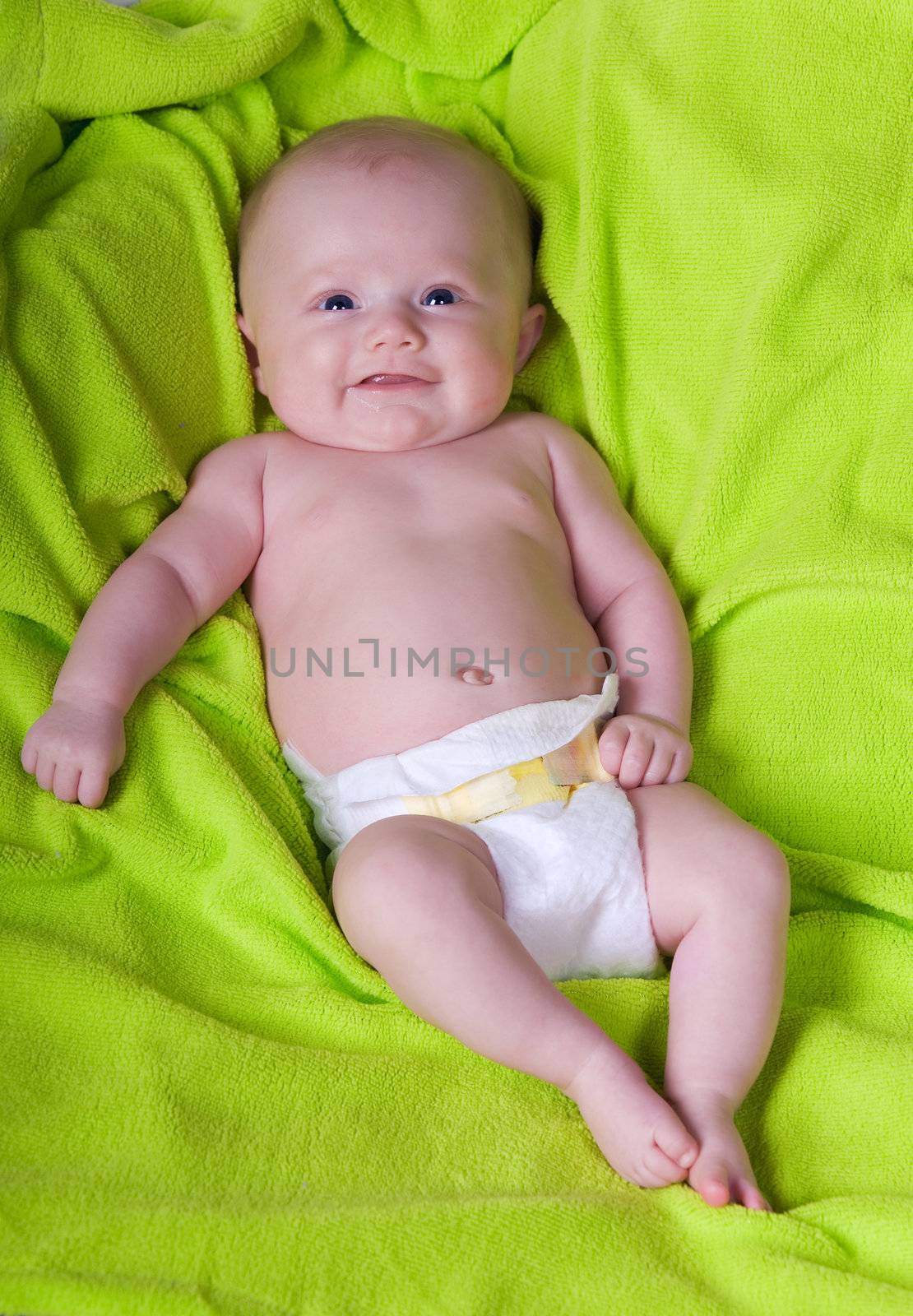 A smiling newborn baby on a green towel. 