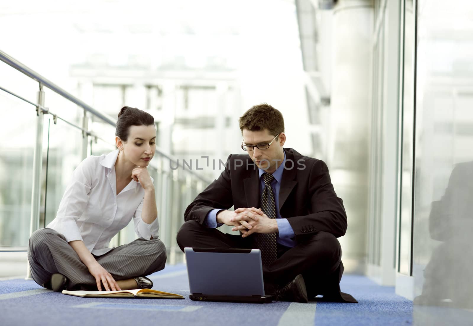 Businesscouple portrait - young man and woman working together on the floor of modern office corridor