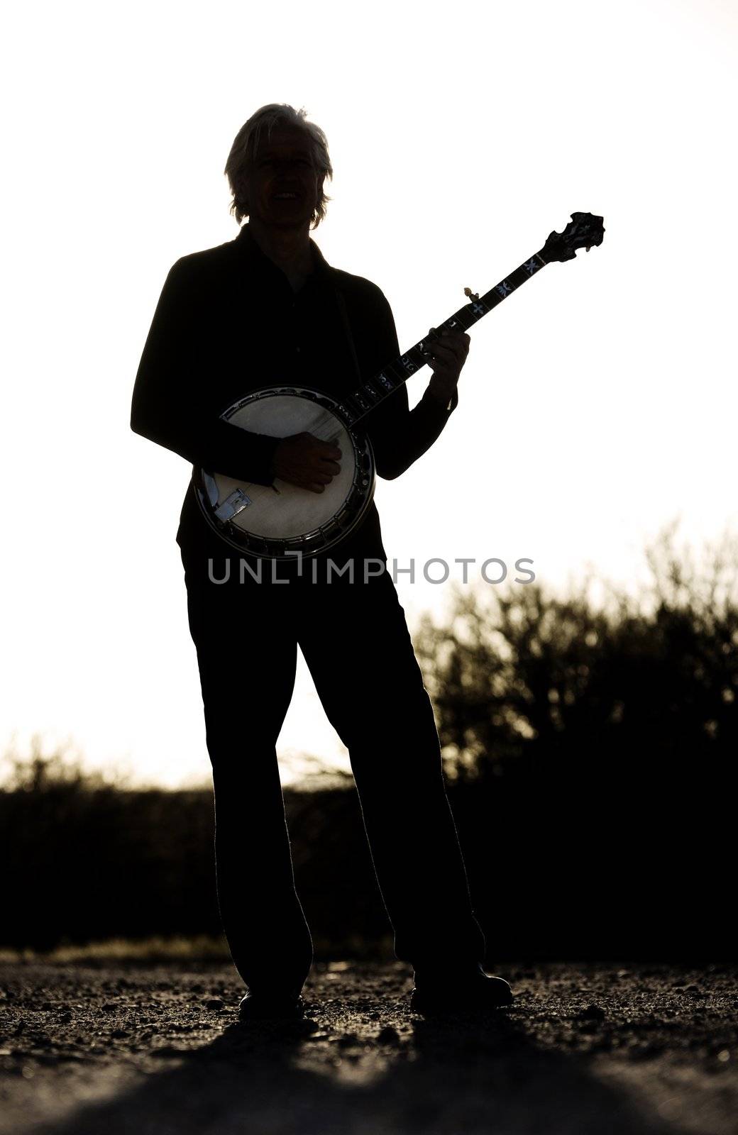 Banjo player with his instrument in silhouette