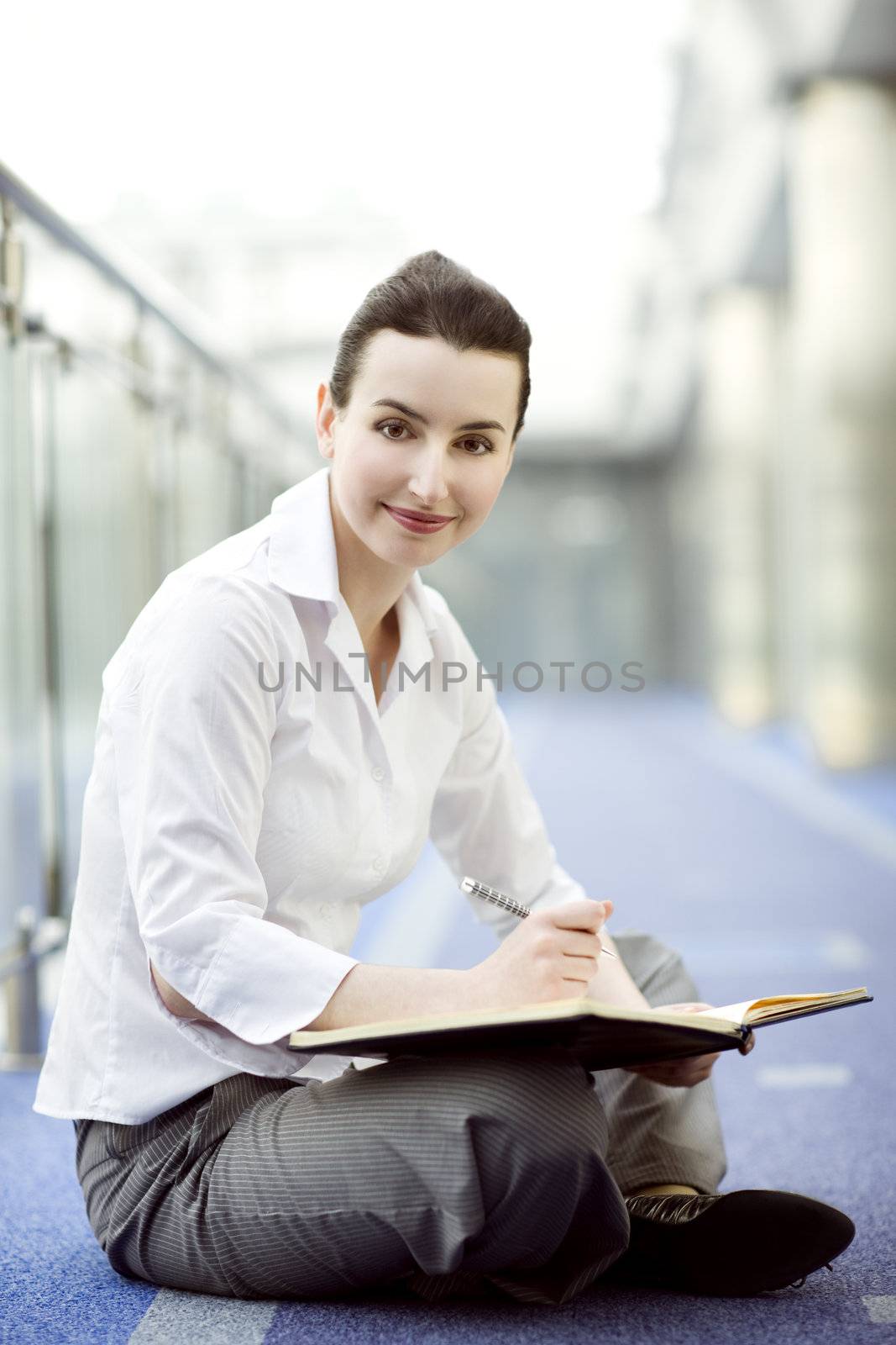 Businesswoman is sitting on the floor with a calendar on hewr lap