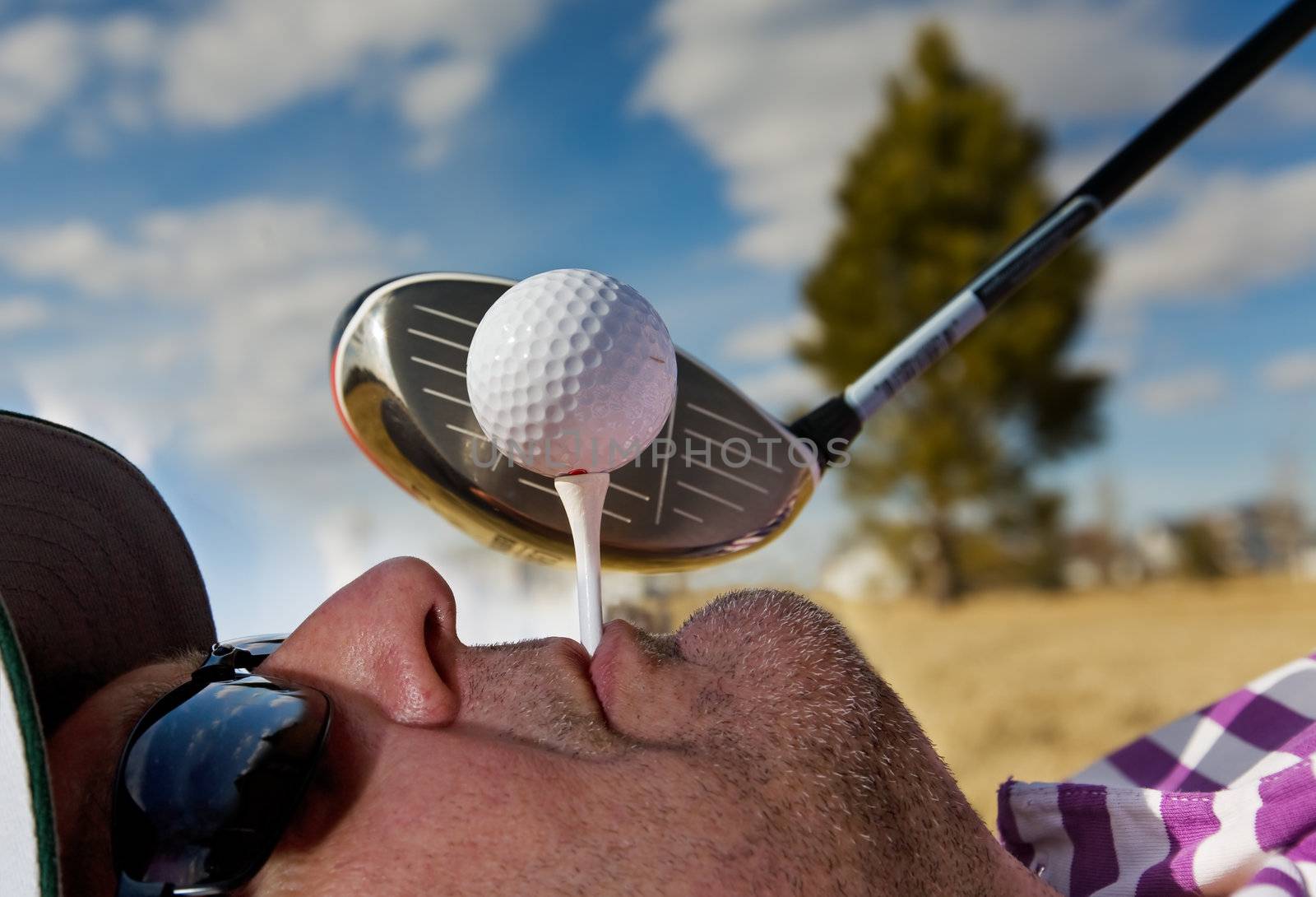 A golfer holding a tee in his mouth