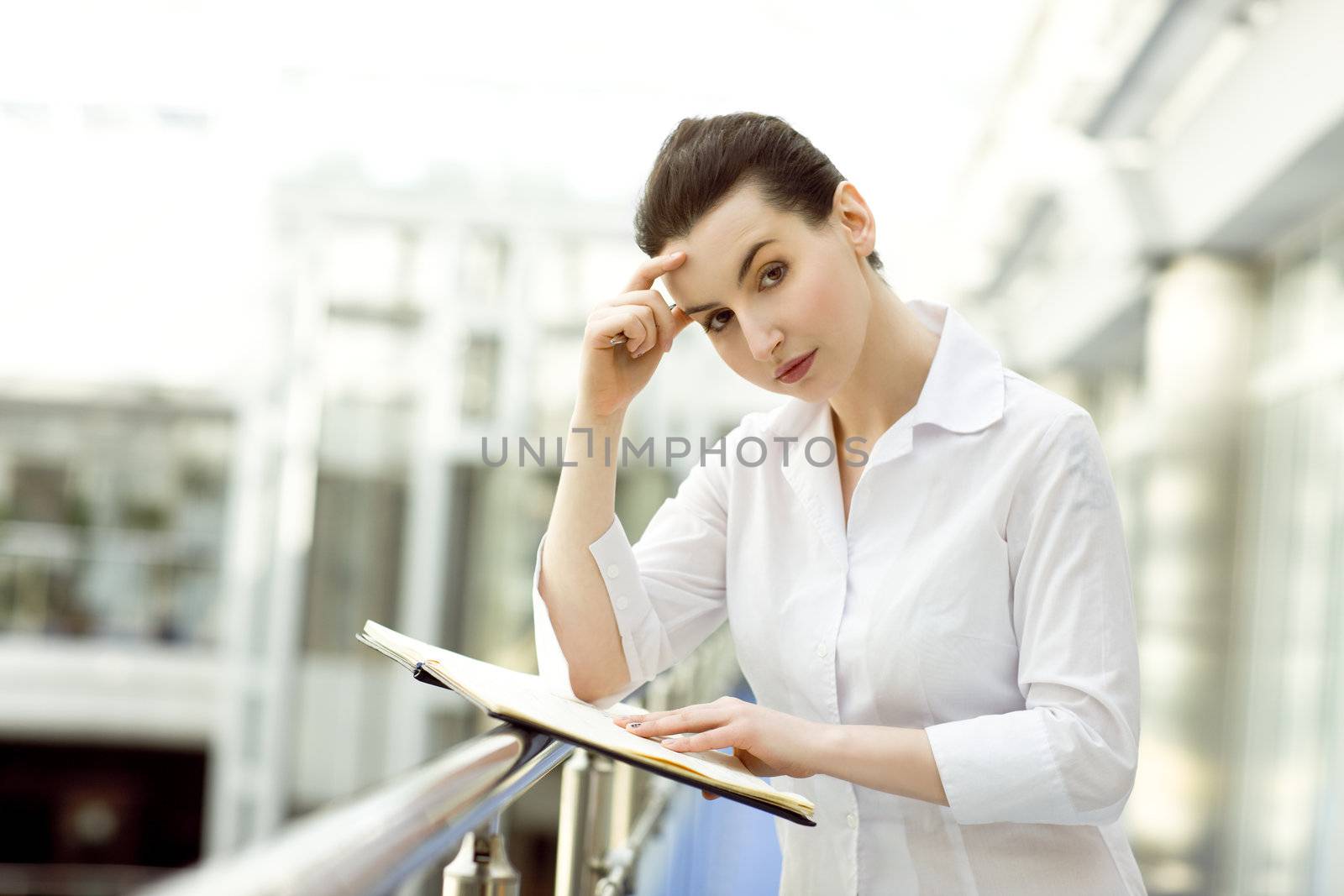 Portrait of young woman standing with business diary