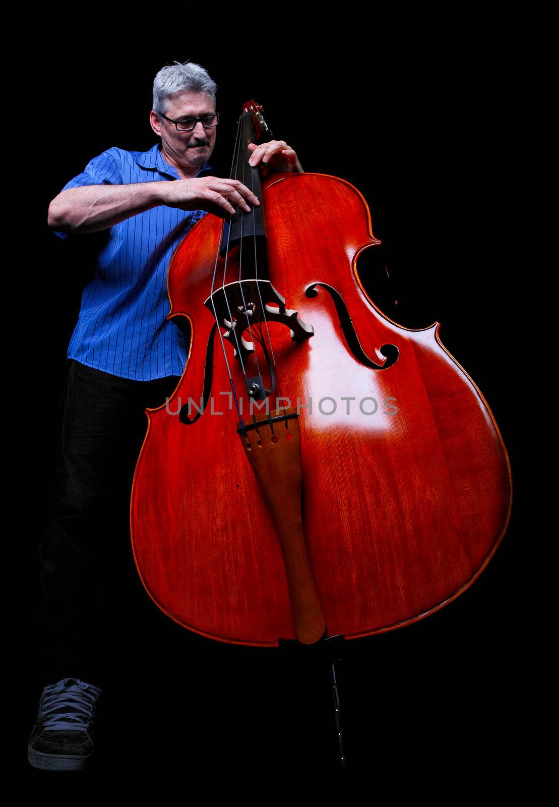 A musician playing a double bass low angle shot on a black background