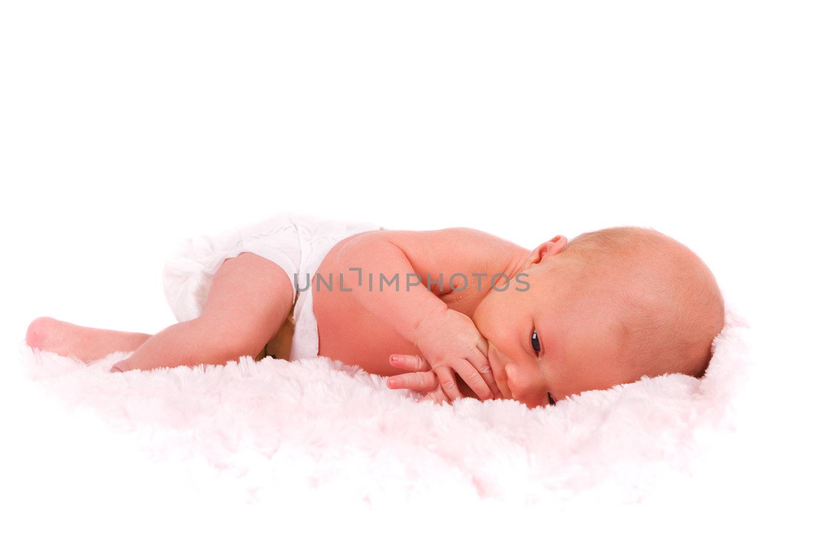 A newborn baby in diapers sucking on her fingers