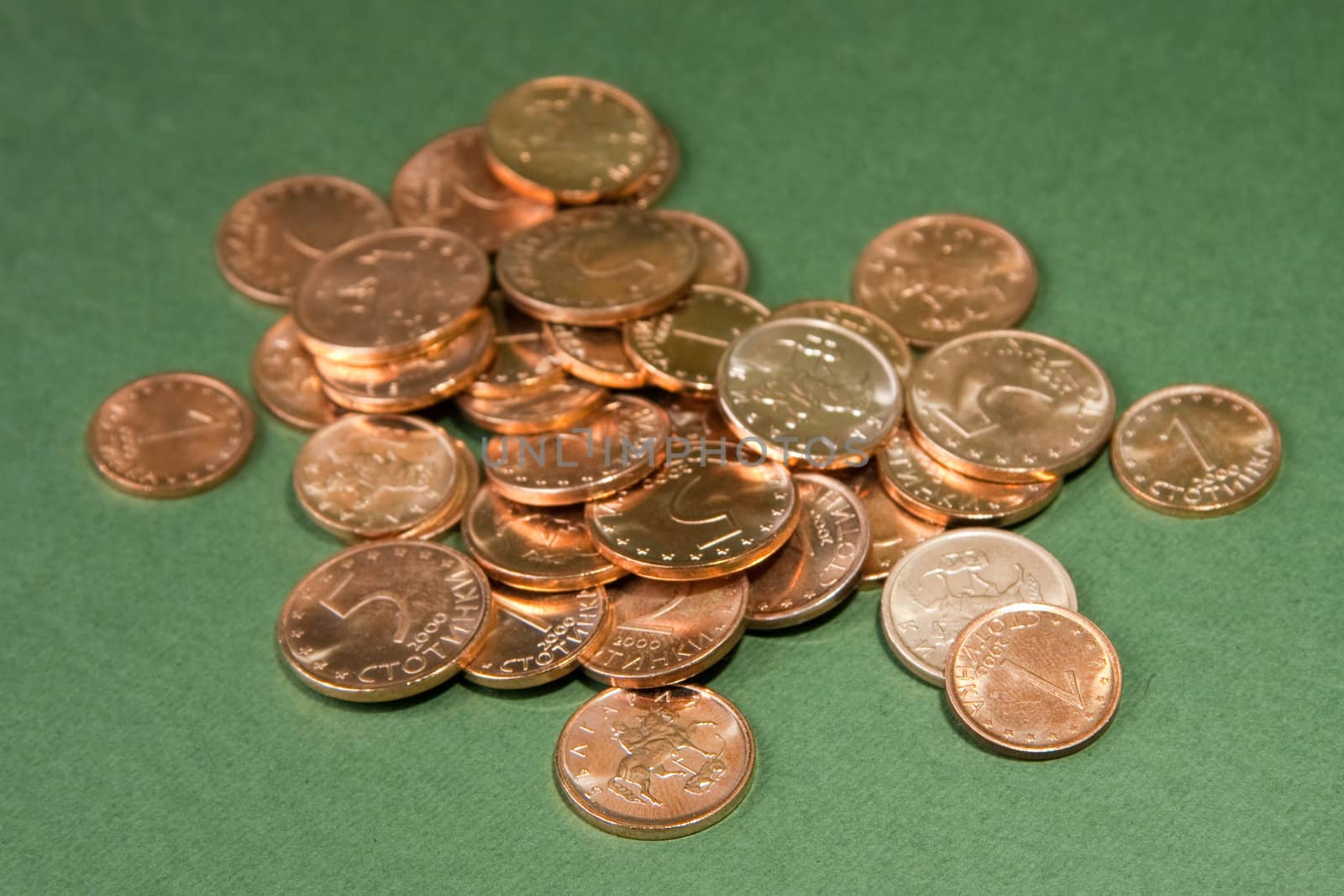 Pile of coins from Bulgaria on a green background, called stotinki. Nominals one, two and five.