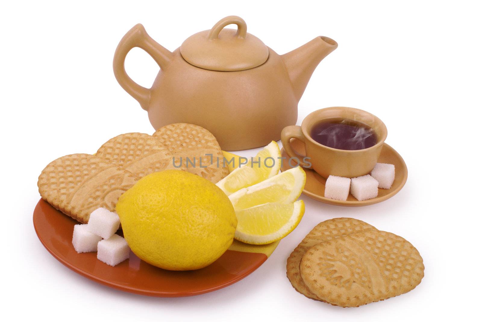 set of the earthenware teapot, cups of tea, lump shugar, sliced lemon and biscuits isolated on white background with clipping path               