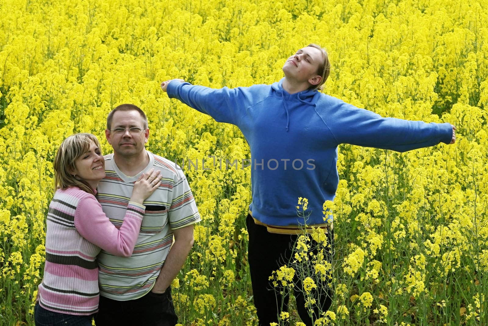Happy middle-aged couple and their son in flower meadow.