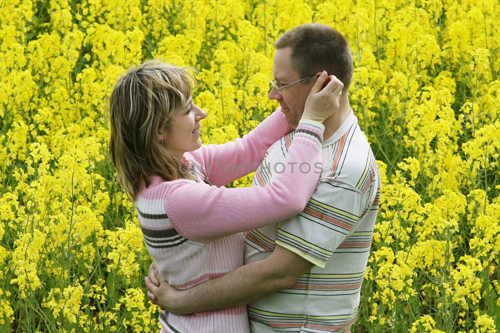 Happy and smiling middle-aged couple in the flower meadow.
