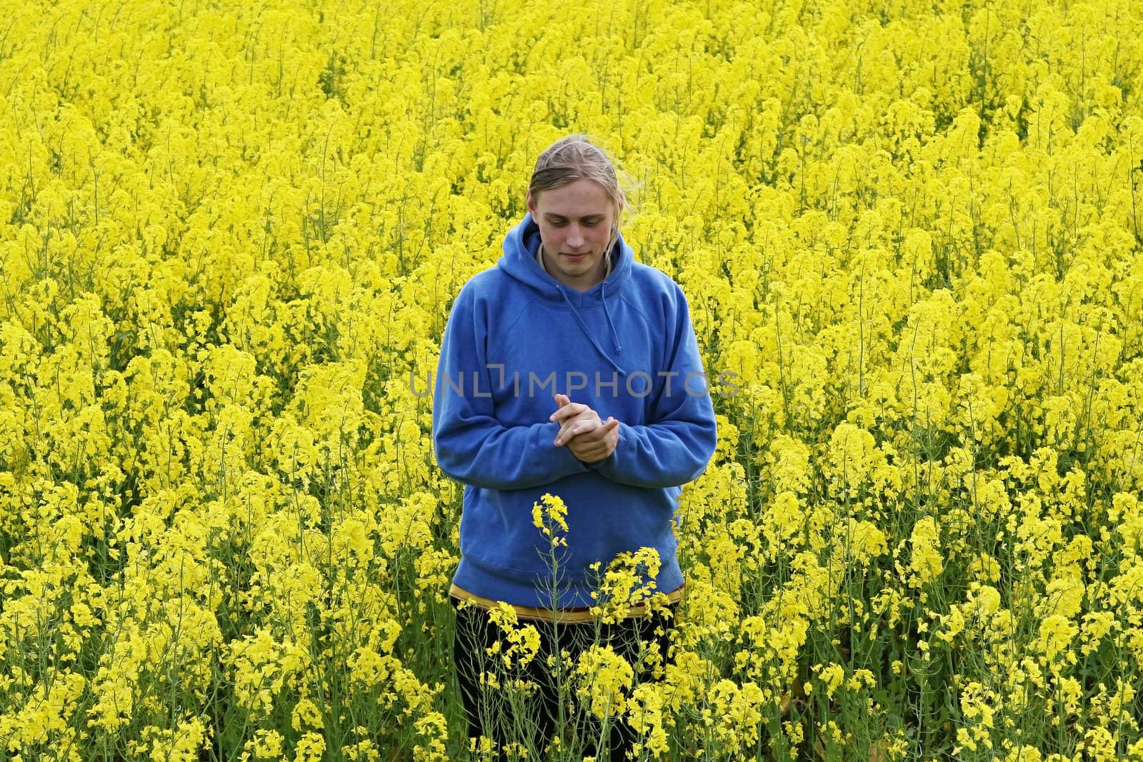 Happy young man in the yellow flower meadow.