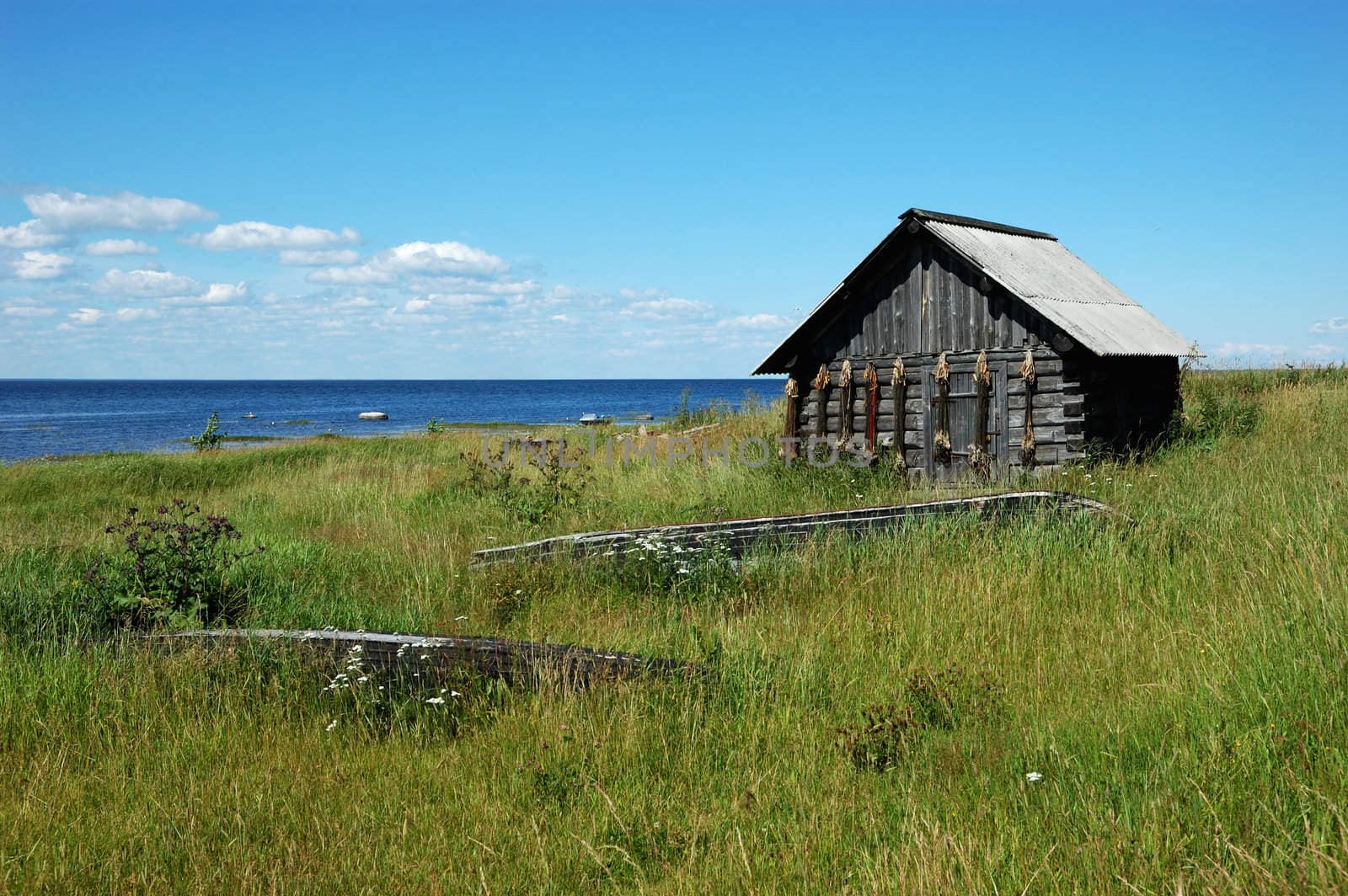 Old wooden shed with fishing cordages and old wooden boats on the lake bank, north Russia