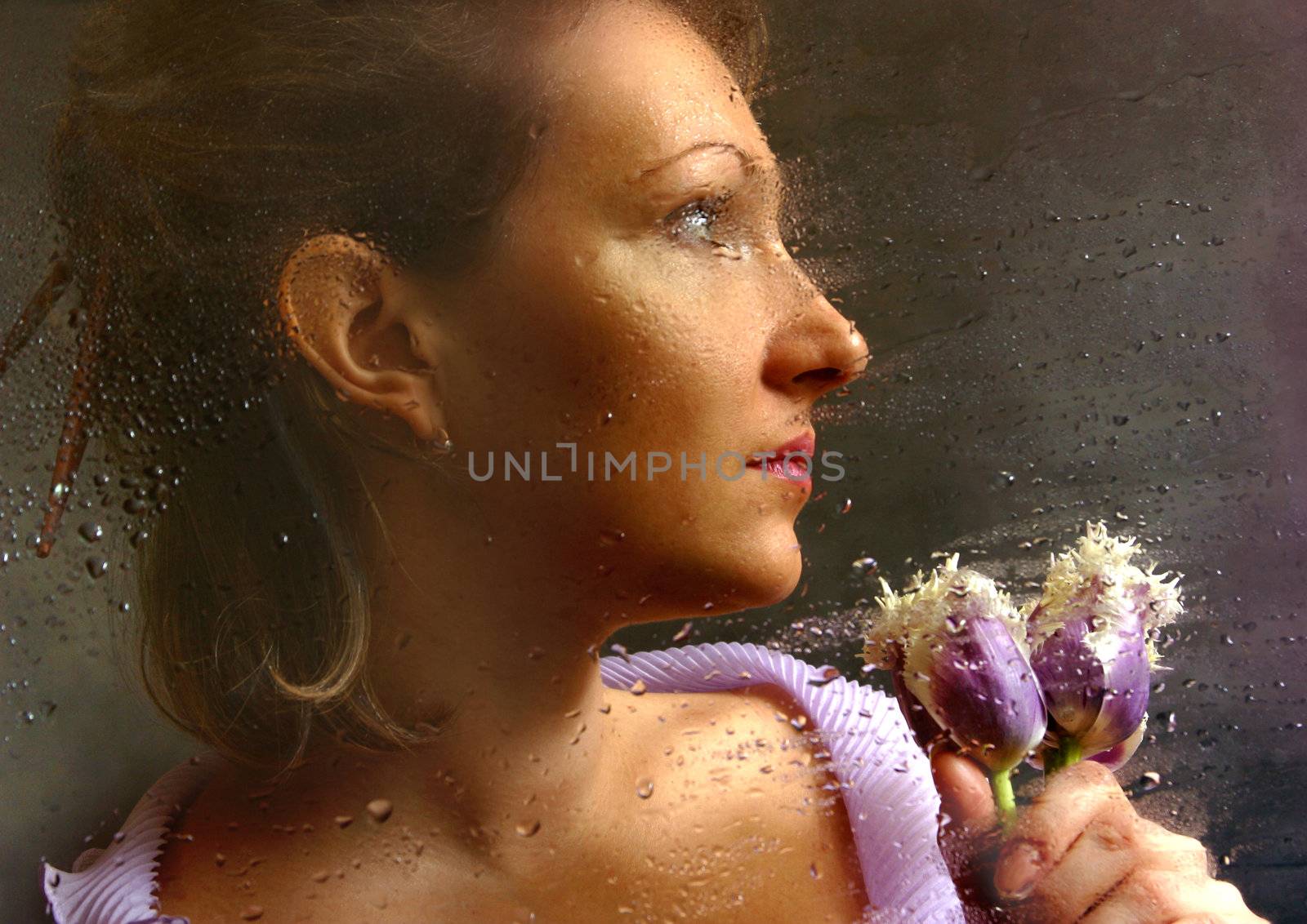 The woman with tulips behind of a damp window