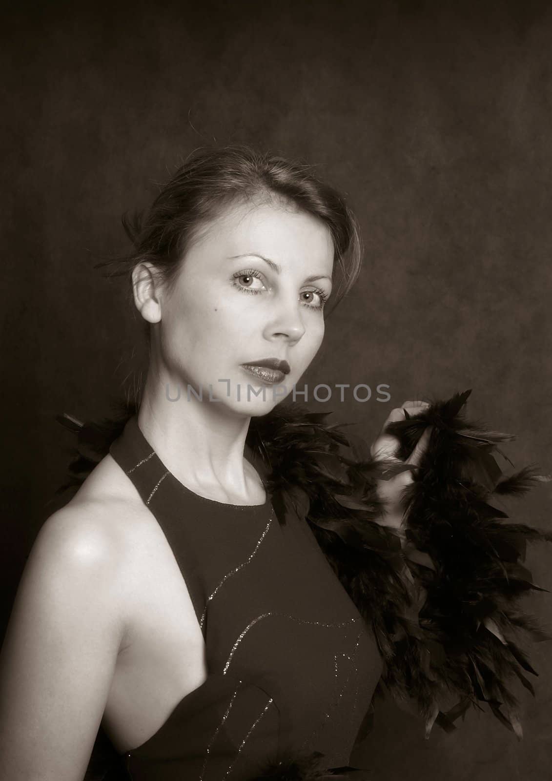 Portrait of the beautiful woman in an evening dress with feathers. b/w+sepia