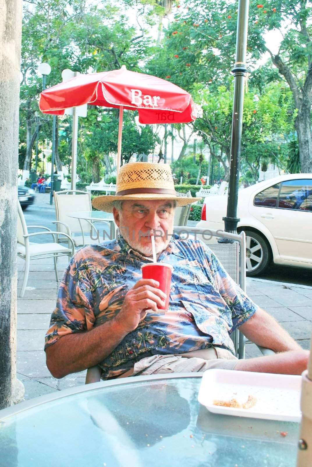 Mature male drinking beverage on street side cafe next to park