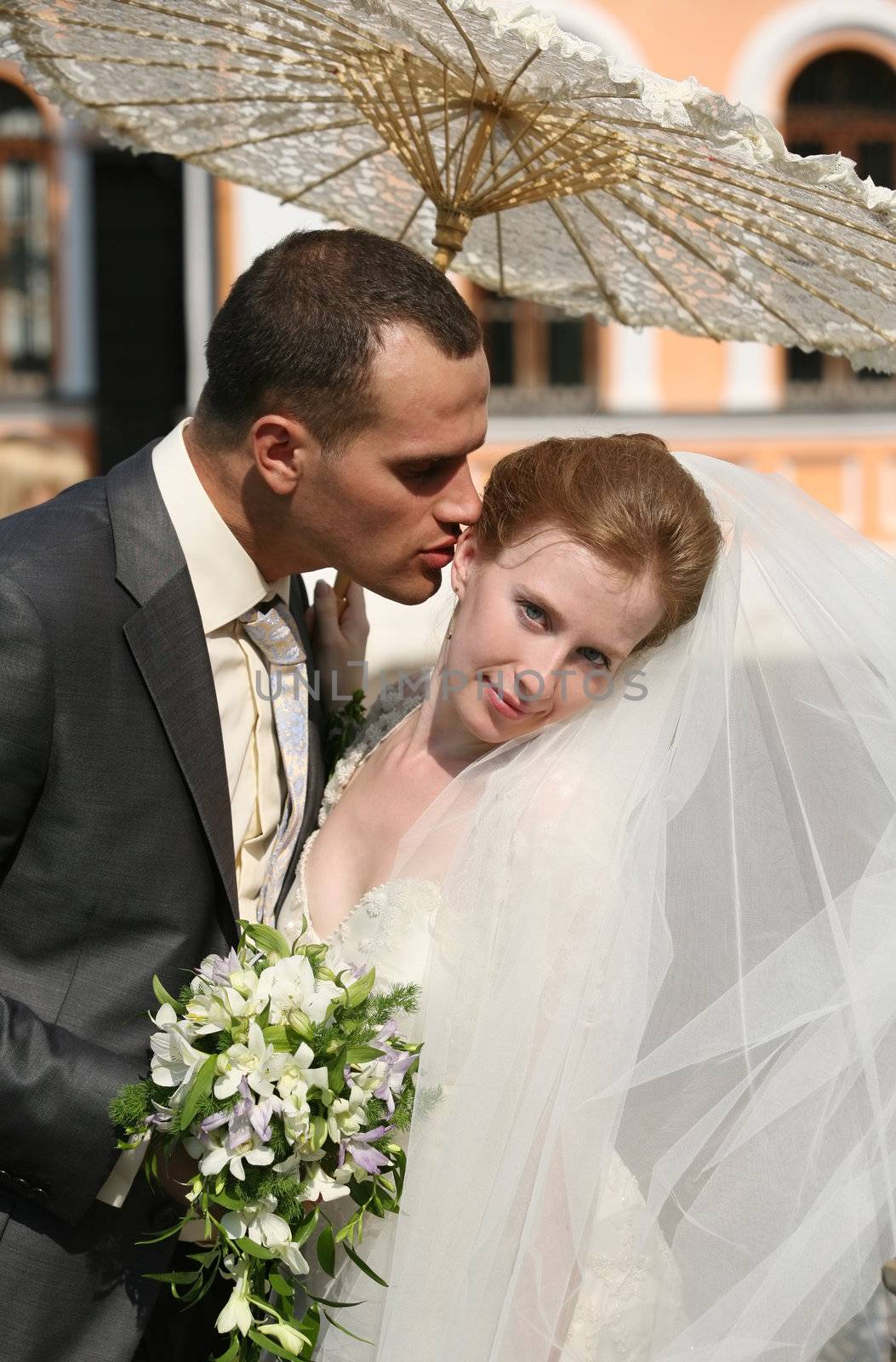 The groom and the bride kiss in park