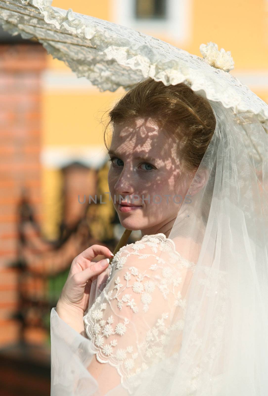 The beautiful bride closed by a umbrella from the sun